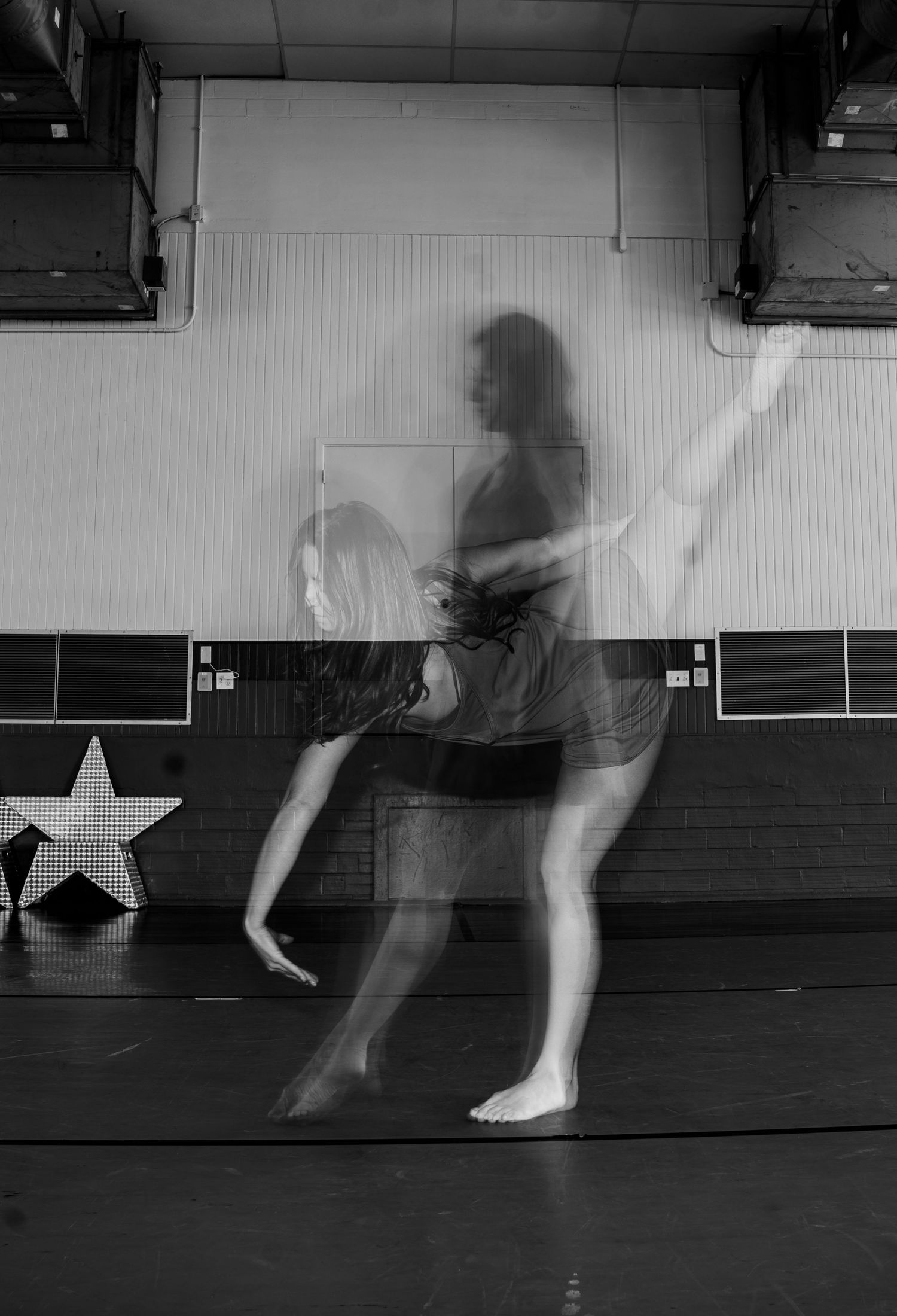 A sequence of black and white motion blur photos showing a dancer's legs in movement across a studio floor.
