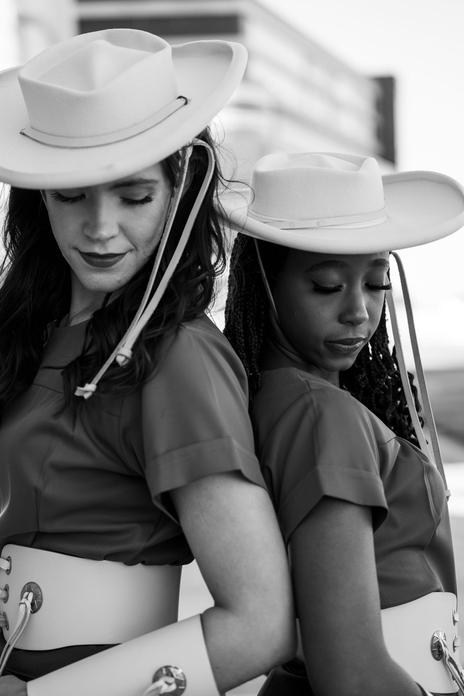 Black and white photo series showing two people in cowboy hats and dark outfits posing together.