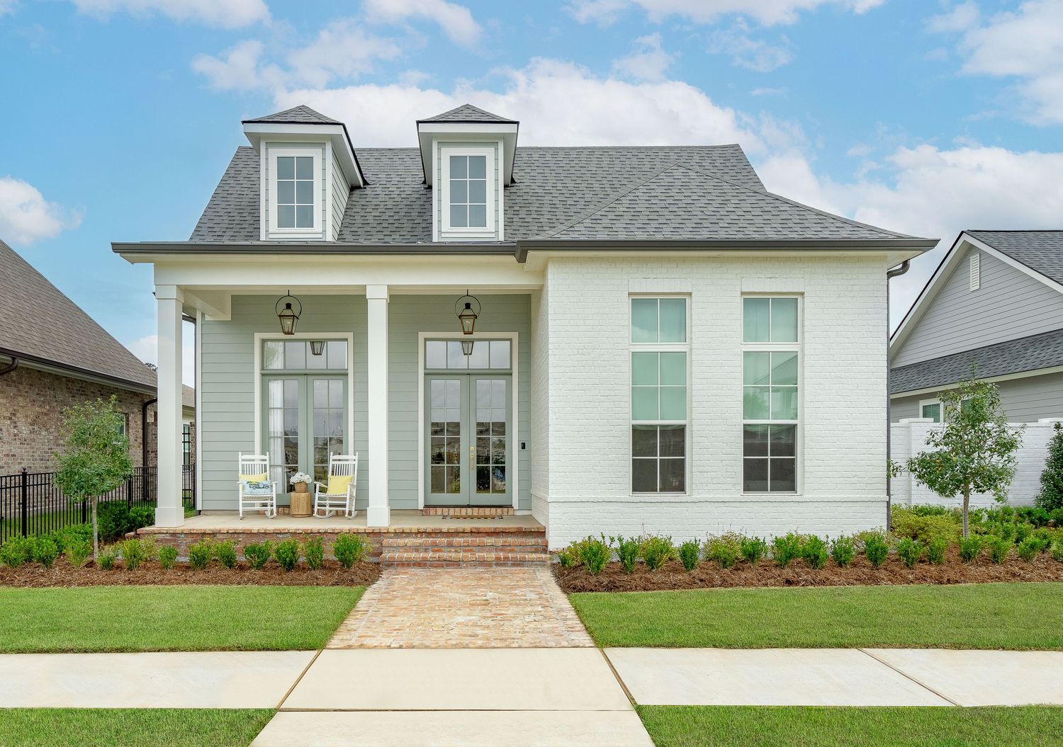 White modern farmhouse style home with dormer windows and professional landscaping.
