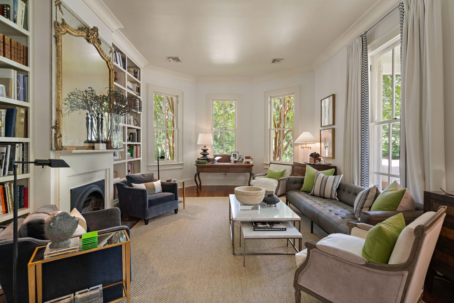Modern living room with built-in bookshelves, gray sofa, and green accent pillows in bright natural light.