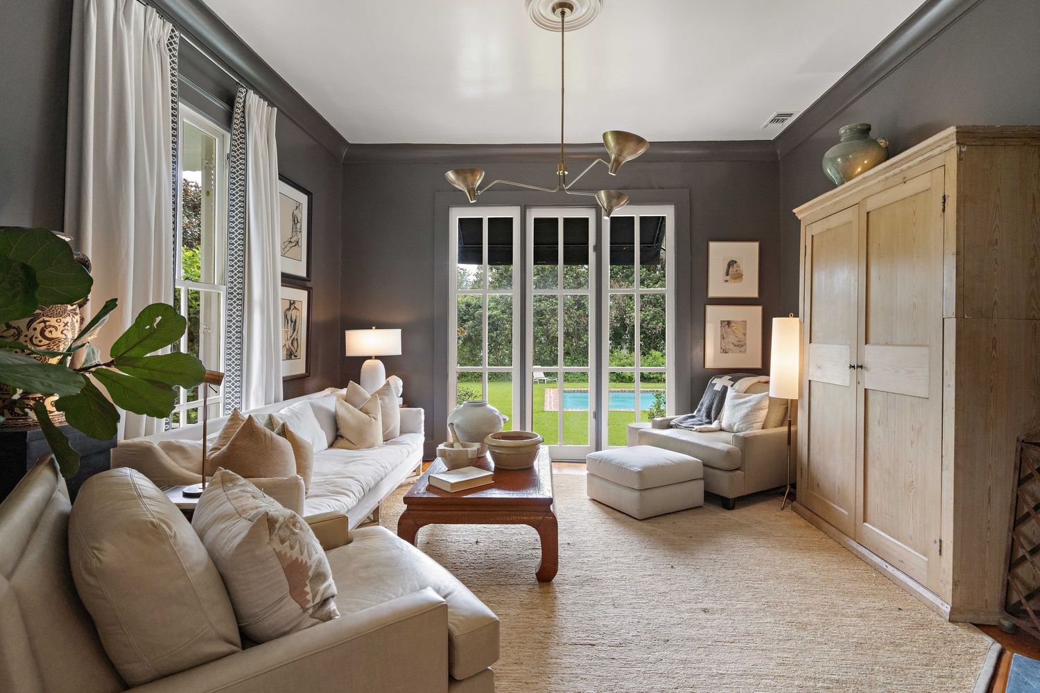 Bright living room with comfortable white sofas, large windows, and built-in storage in neutral tones.