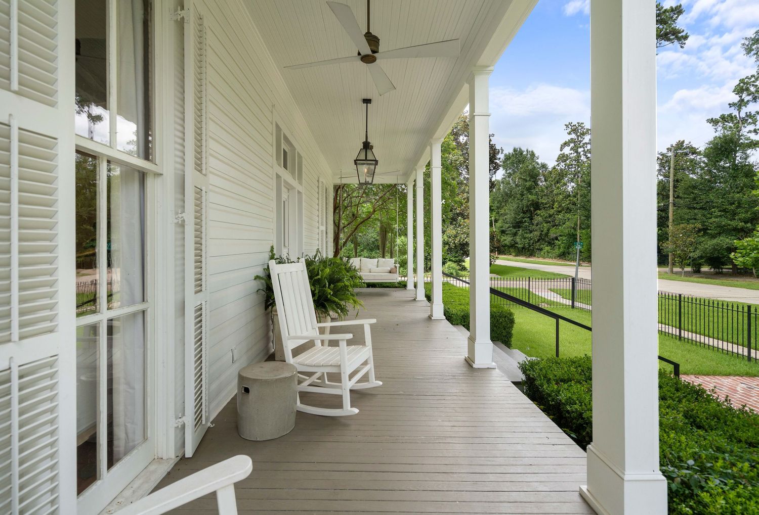 Classic white Southern porch with rocking chairs and colonial columns overlooking a manicured lawn.
