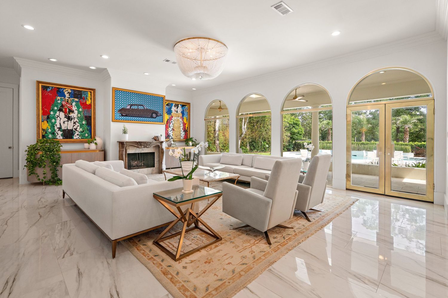 Luxurious living room with white sofas, arched windows, marble floors, and elegant crystal chandelier.