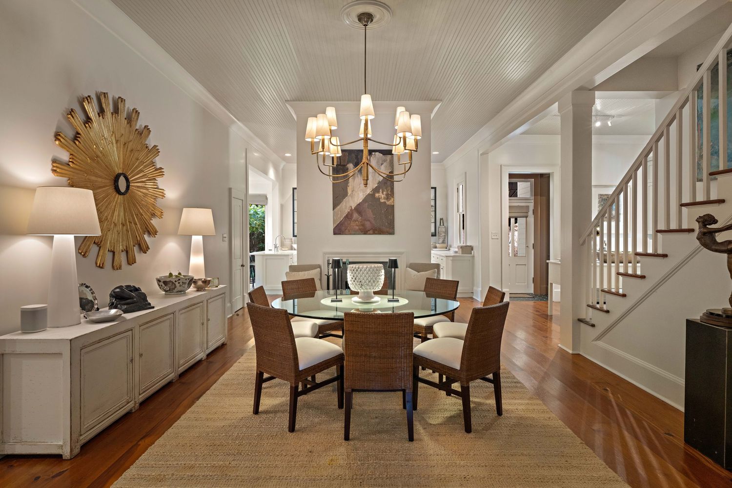 Elegant dining room with round table, brown leather chairs, and dramatic sunburst mirror wall decor.