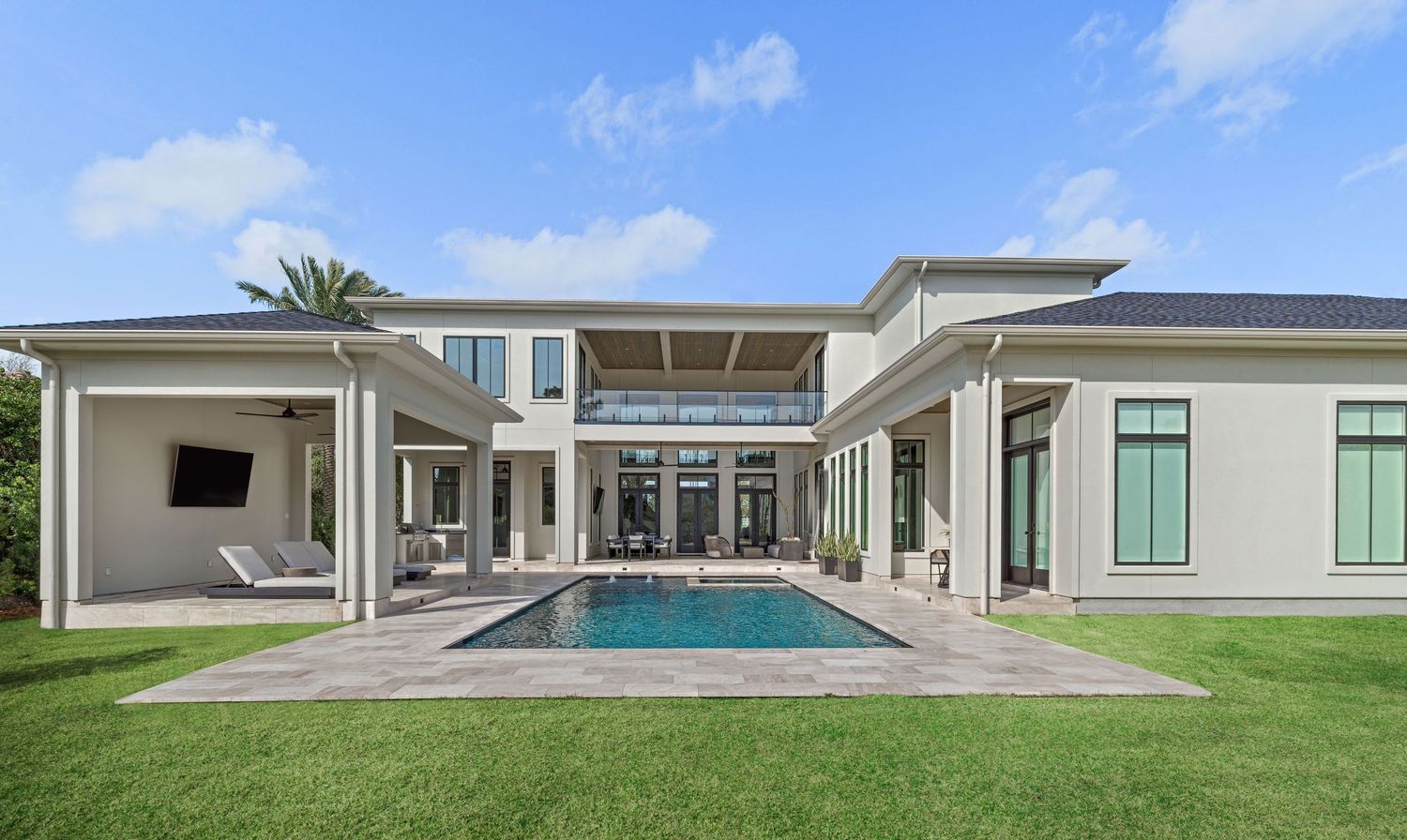 Aerial view of contemporary white house with landscaped lawn and multiple outdoor living spaces.