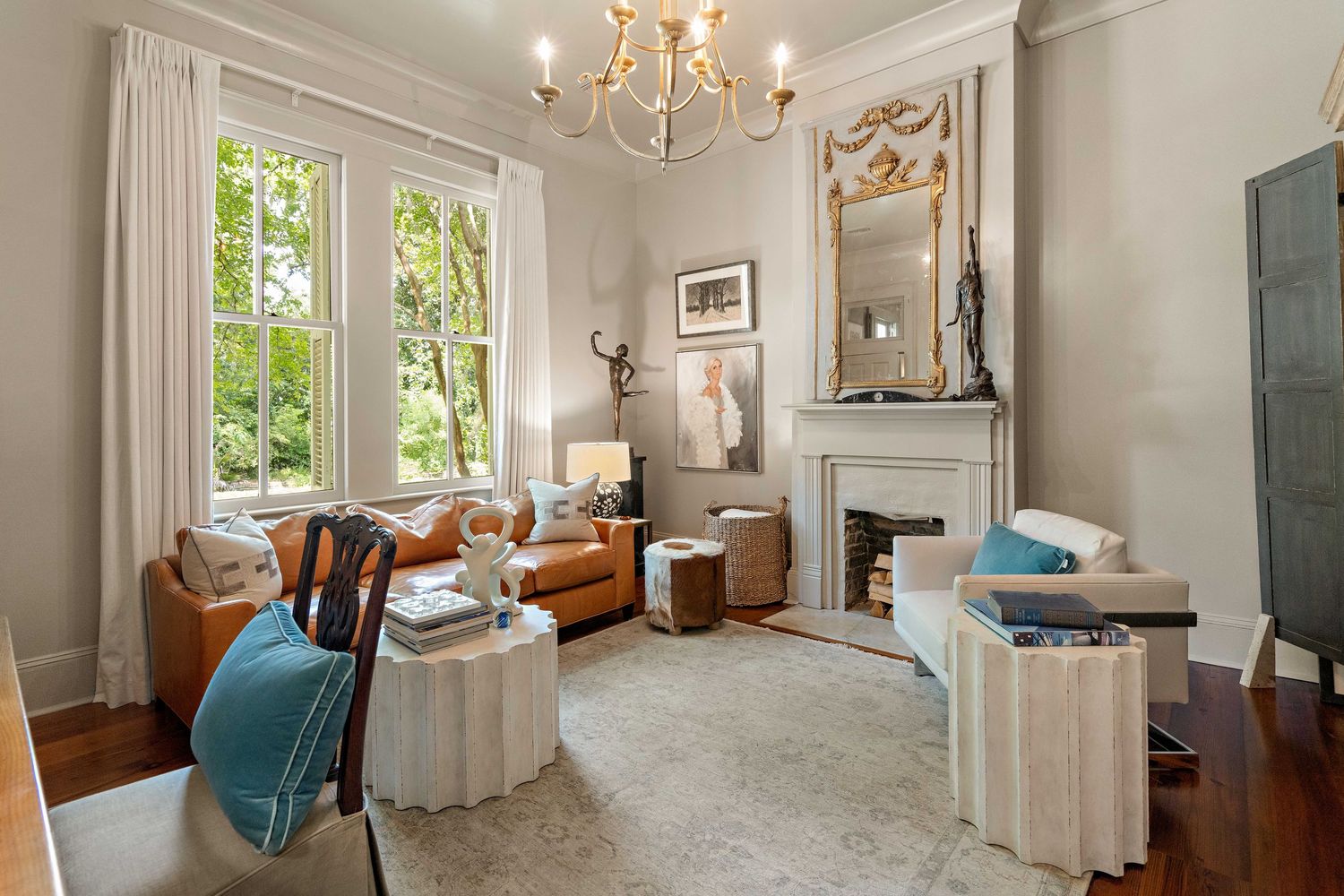 Sophisticated living room with fireplace, blue accents, and large windows letting in natural light.