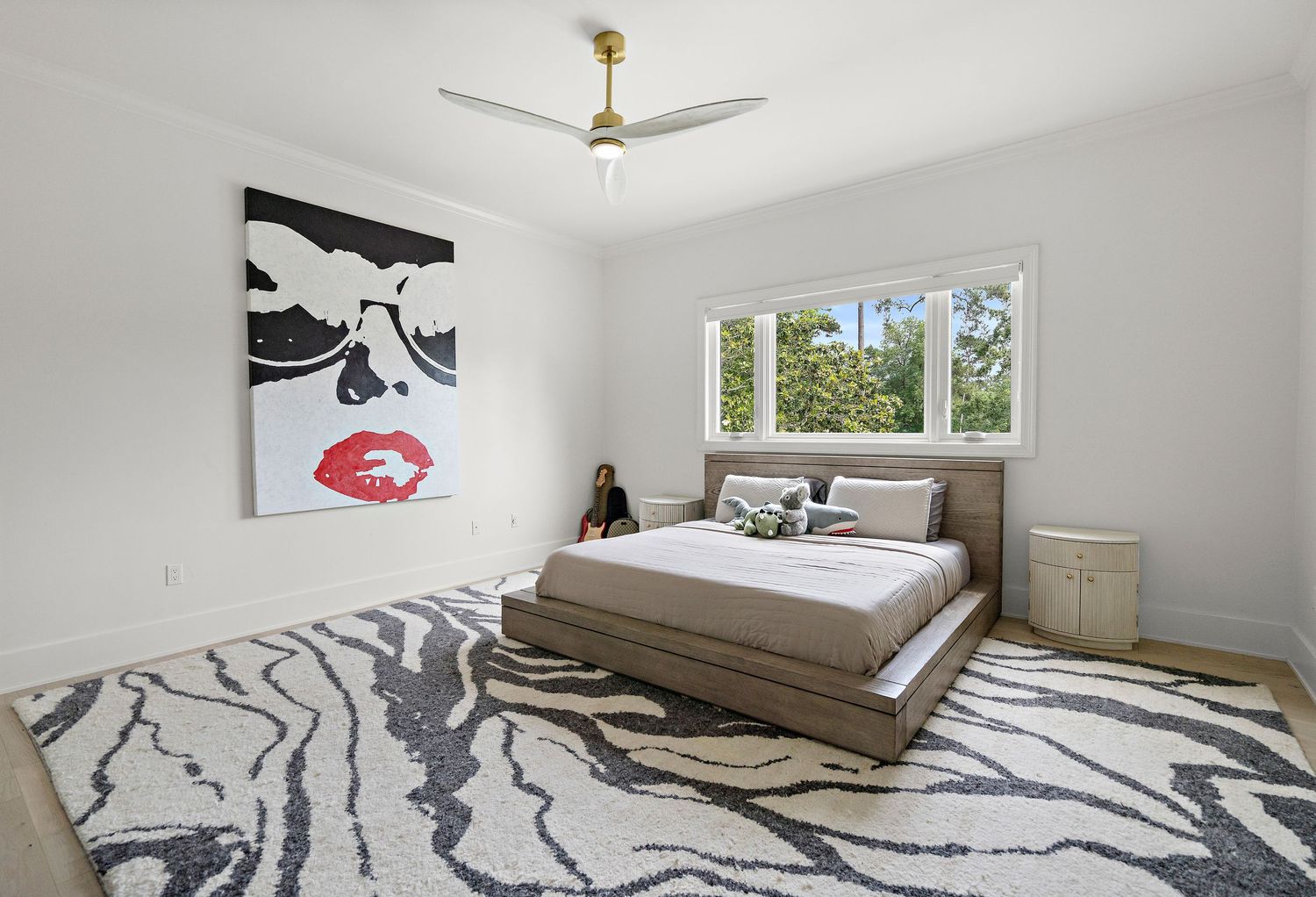 Minimalist bedroom with abstract wall art, platform bed, and geometric patterned area rug.