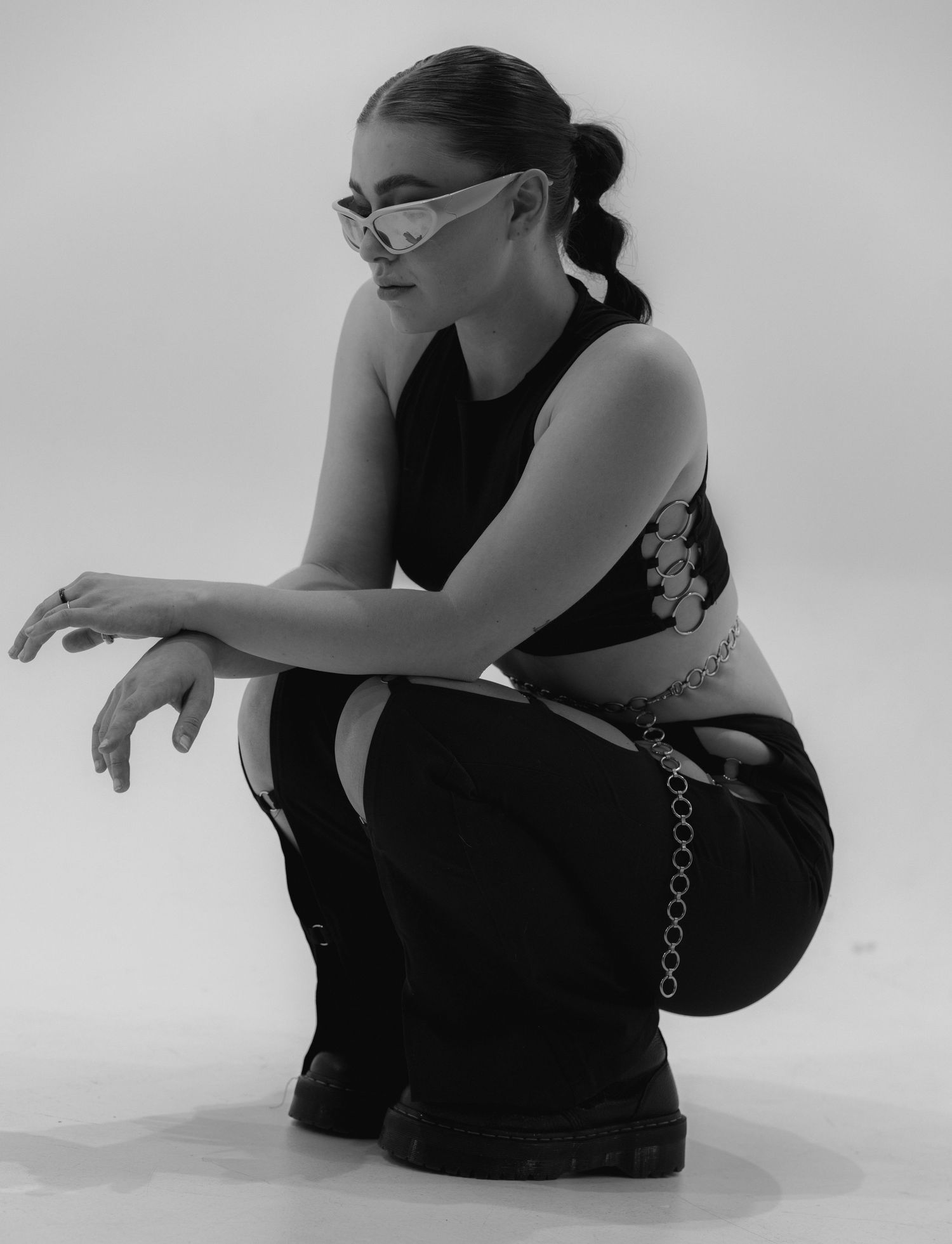 A series of black and white artistic dance poses showing a person in black attire sitting and moving on the ground.