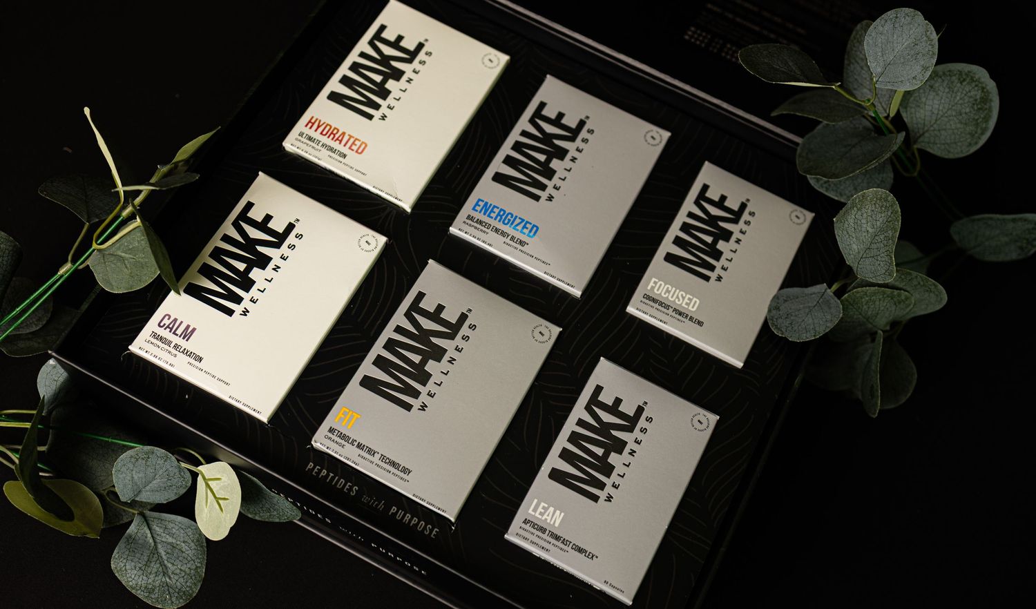 Business cards arranged in a row with green eucalyptus leaves against a dark background.