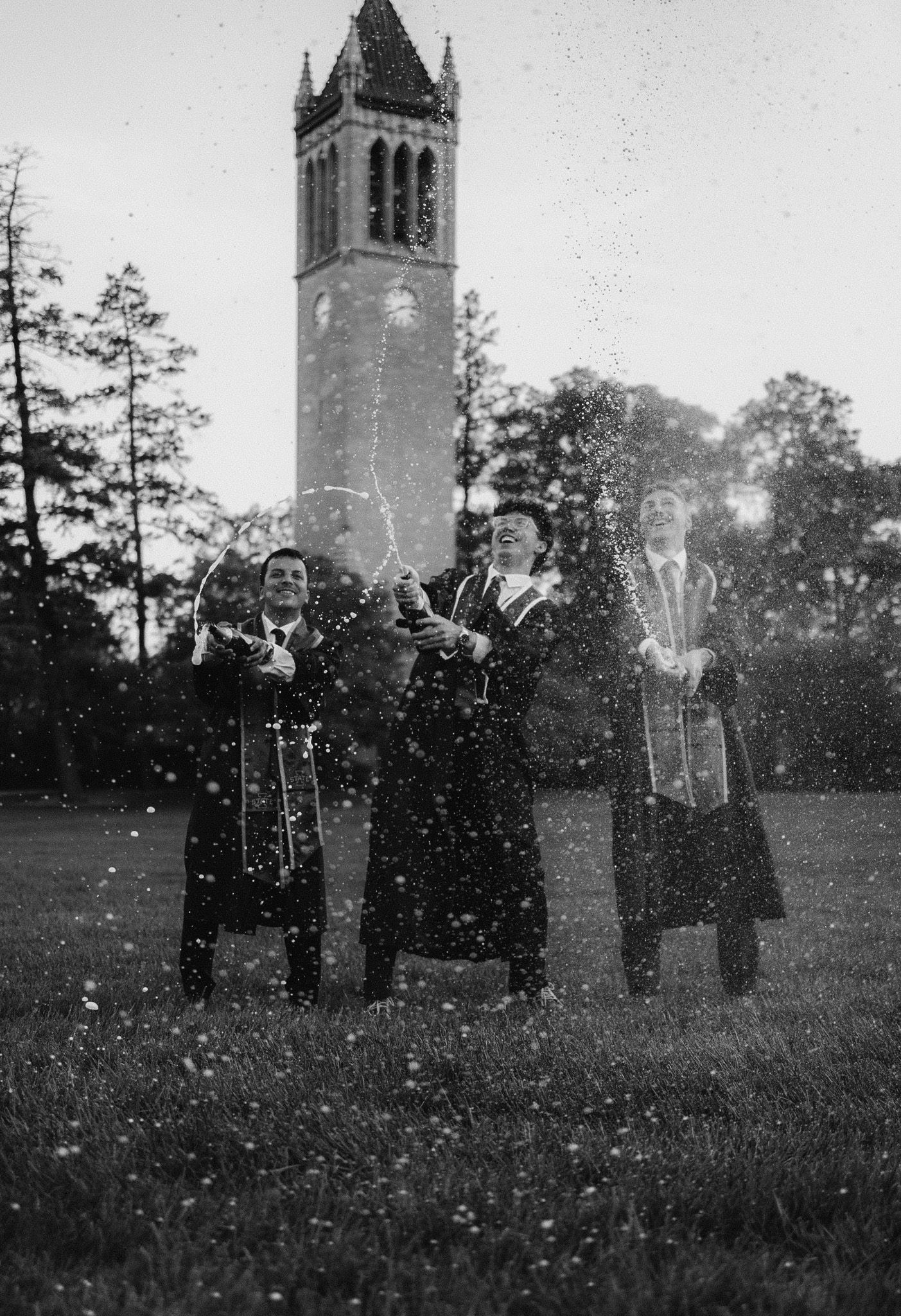 Vintage photo of graduates celebrating with sparklers in front of university tower.
