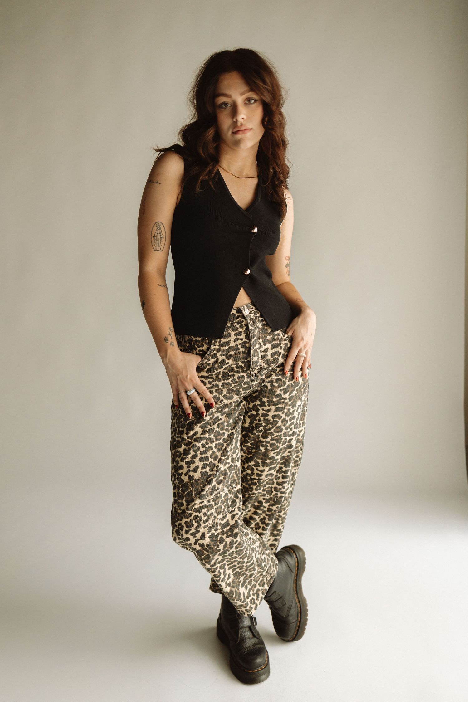 Model crouches in black top and leopard print skirt with boots against white wall showing different dynamic poses.