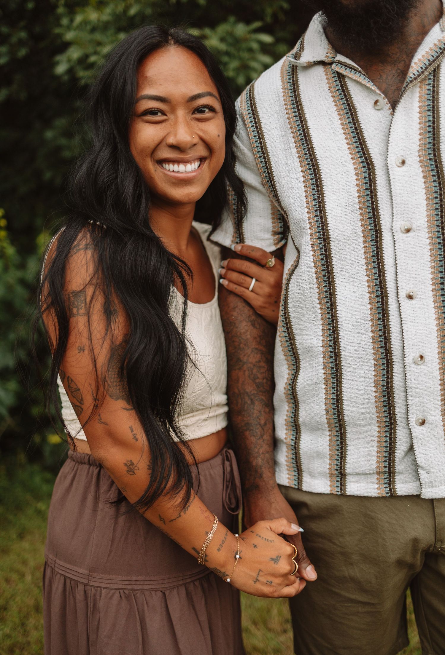 Happy couple wearing coordinating brown and white outfits embracing outdoors during golden hour photoshoot.