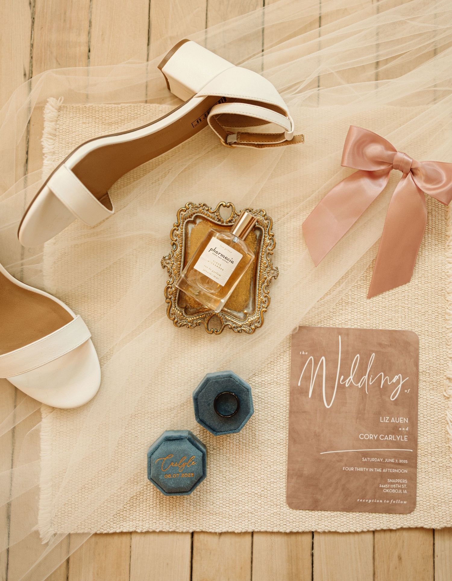 Pink and beige wedding invitation stationery with wax seals and delicate ribbons arranged on a light wooden surface.