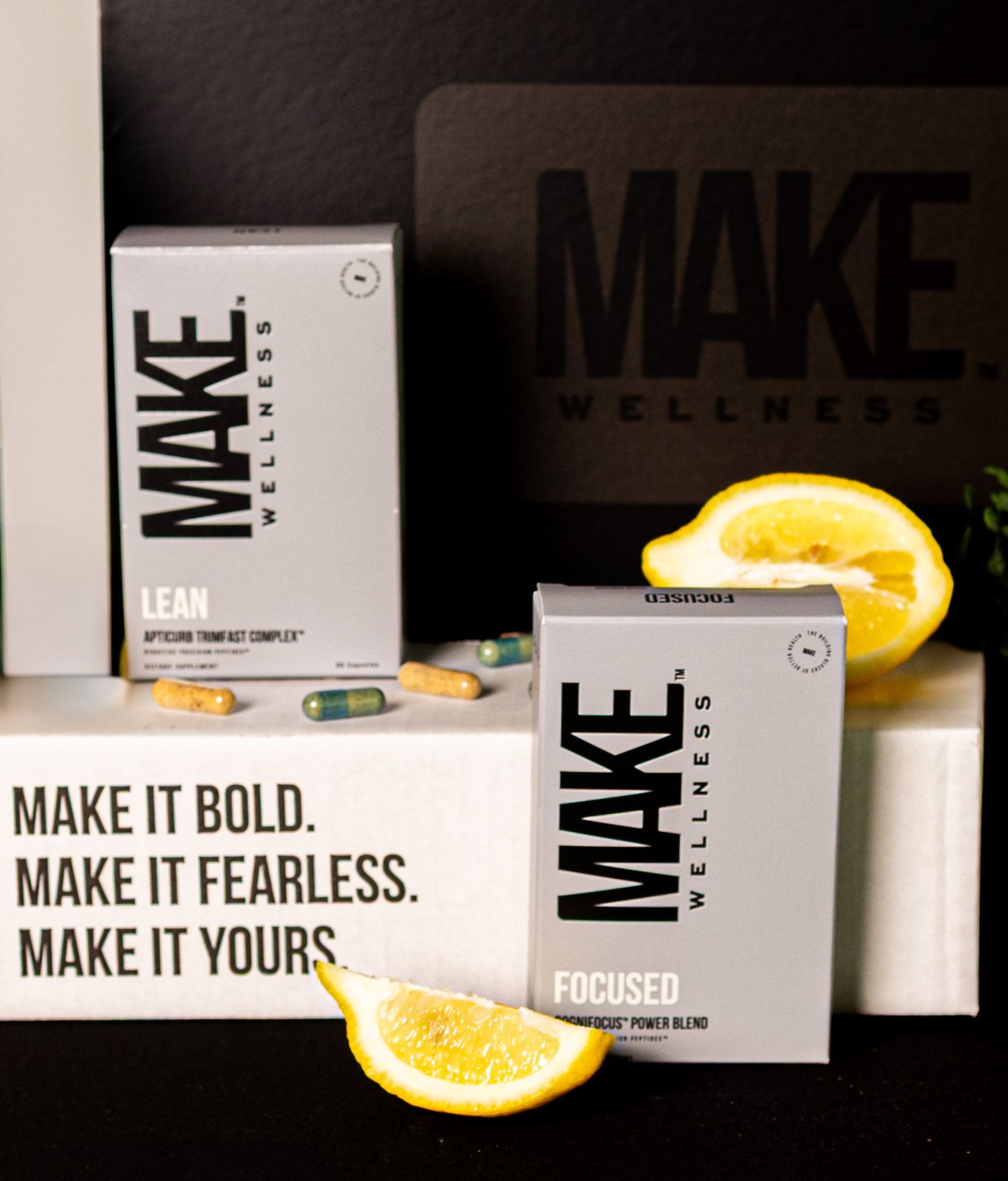 Product display of MAKE wellness supplements with orange slices and bold marketing text against dark background.