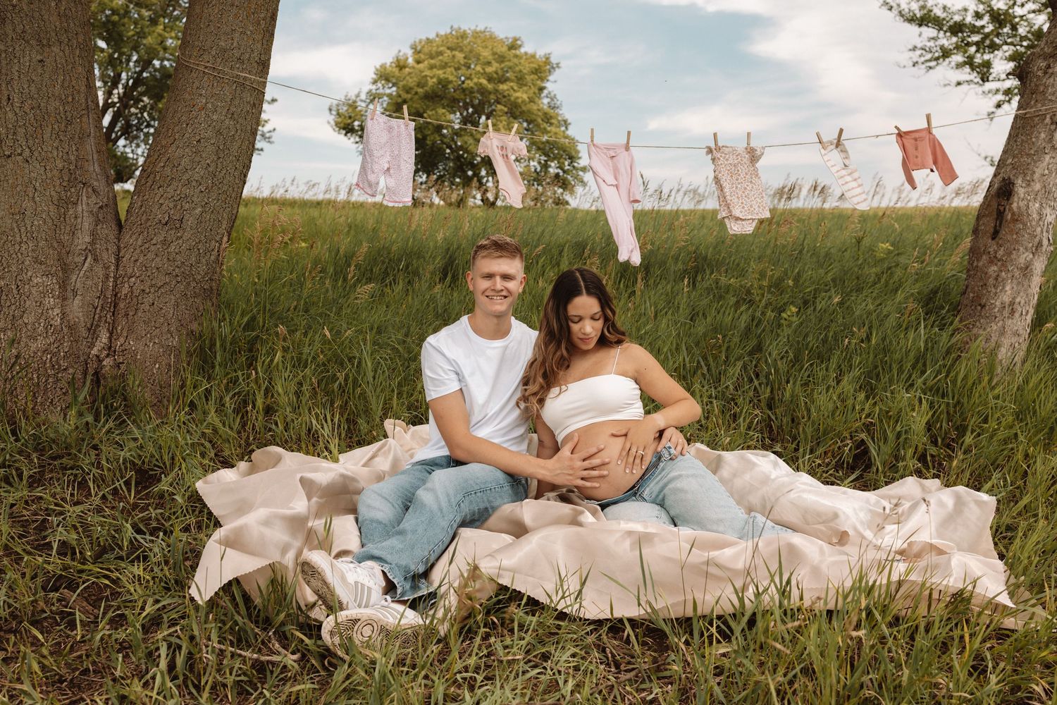 A vintage-inspired maternity photo session in a field with drying laundry hanging on clotheslines during golden hour.
