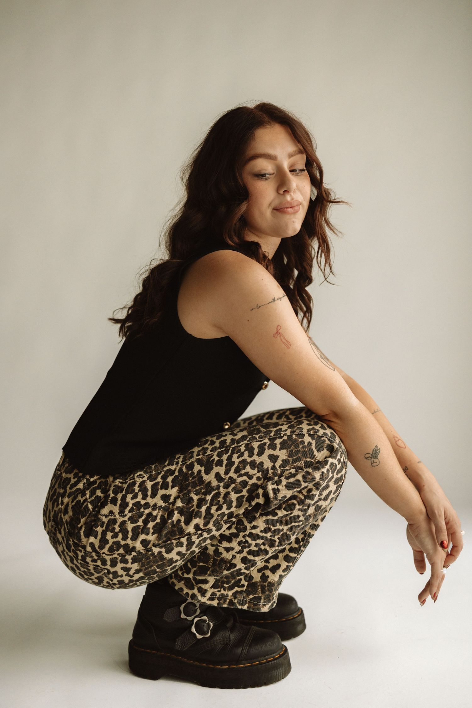 A series of artistic fashion poses showing a model in a black top and leopard print pants against a white background.