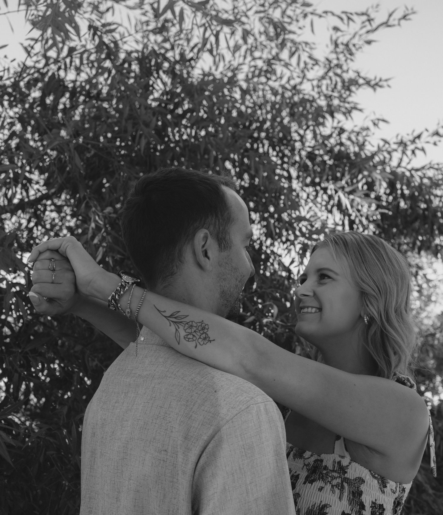 A couple embraces under tree branches in a romantic black and white photo sequence.