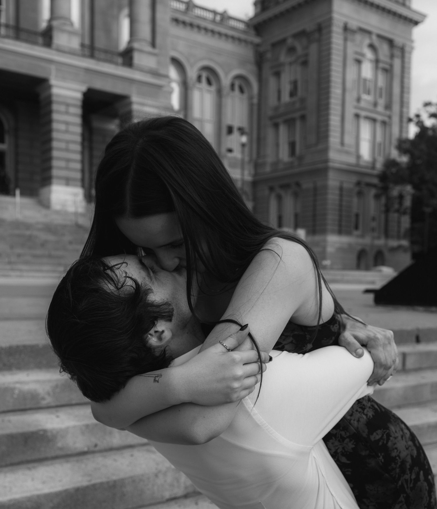 A black and white photo sequence showing two people embracing in front of a grand historic building.