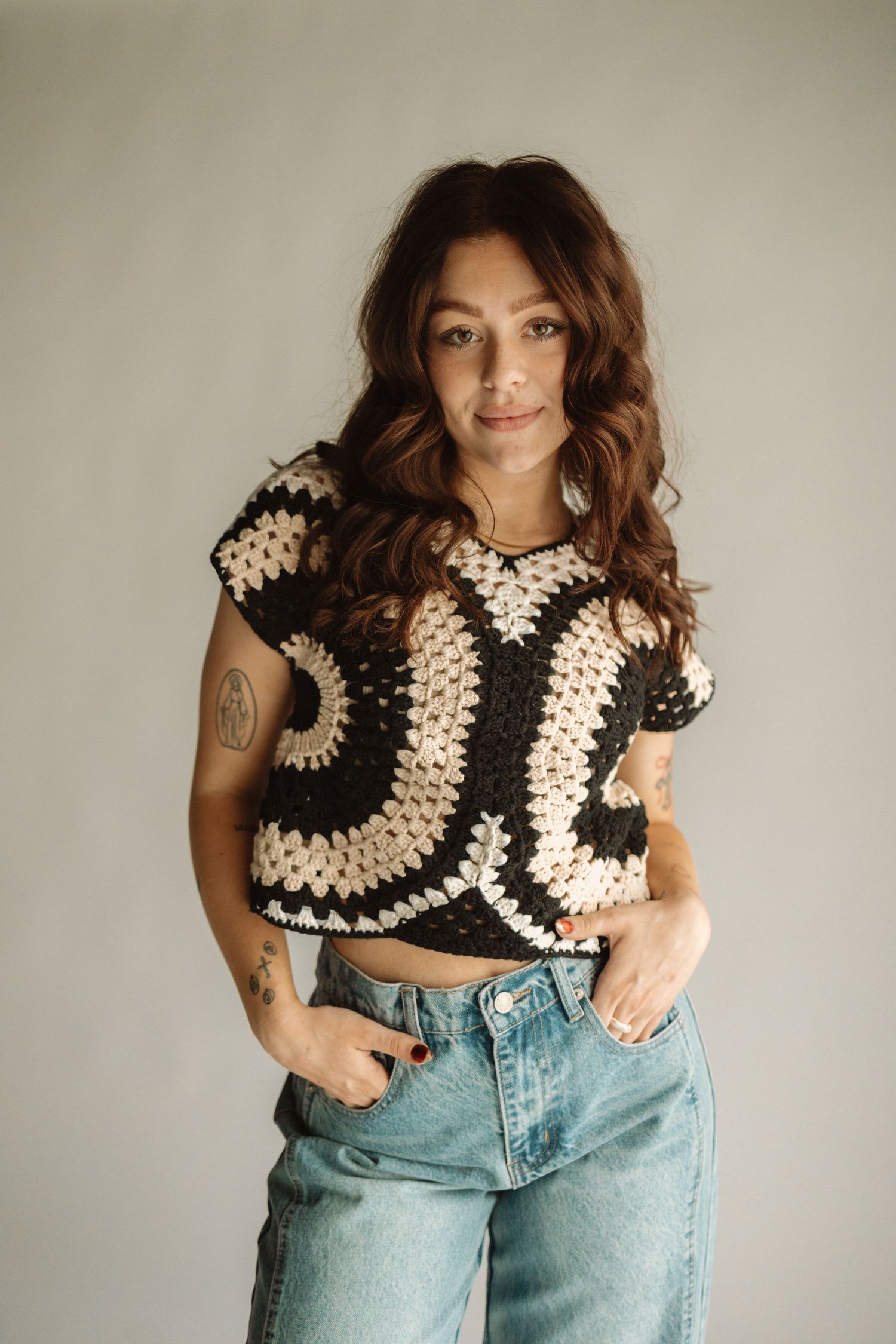 Handmade crochet crop top with black and cream shell design paired with light wash high-waisted jeans in a casual style set.