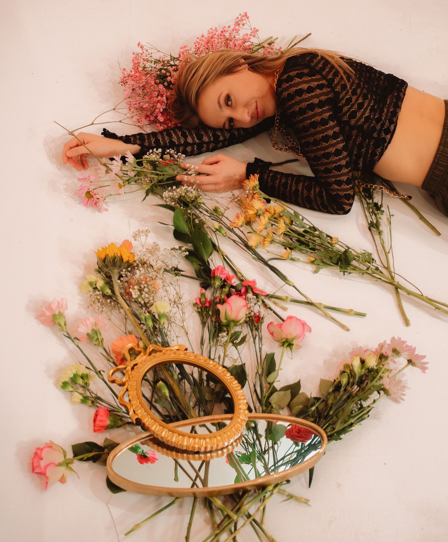Artistic overhead photo with dried flowers and embroidery hoops scattered on pink backdrop with romantic vintage styling.