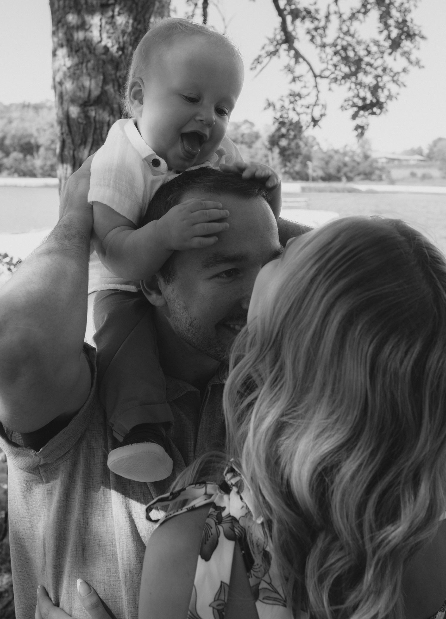 A series of black and white photographs showing tender moments between a parent and child in an outdoor setting.