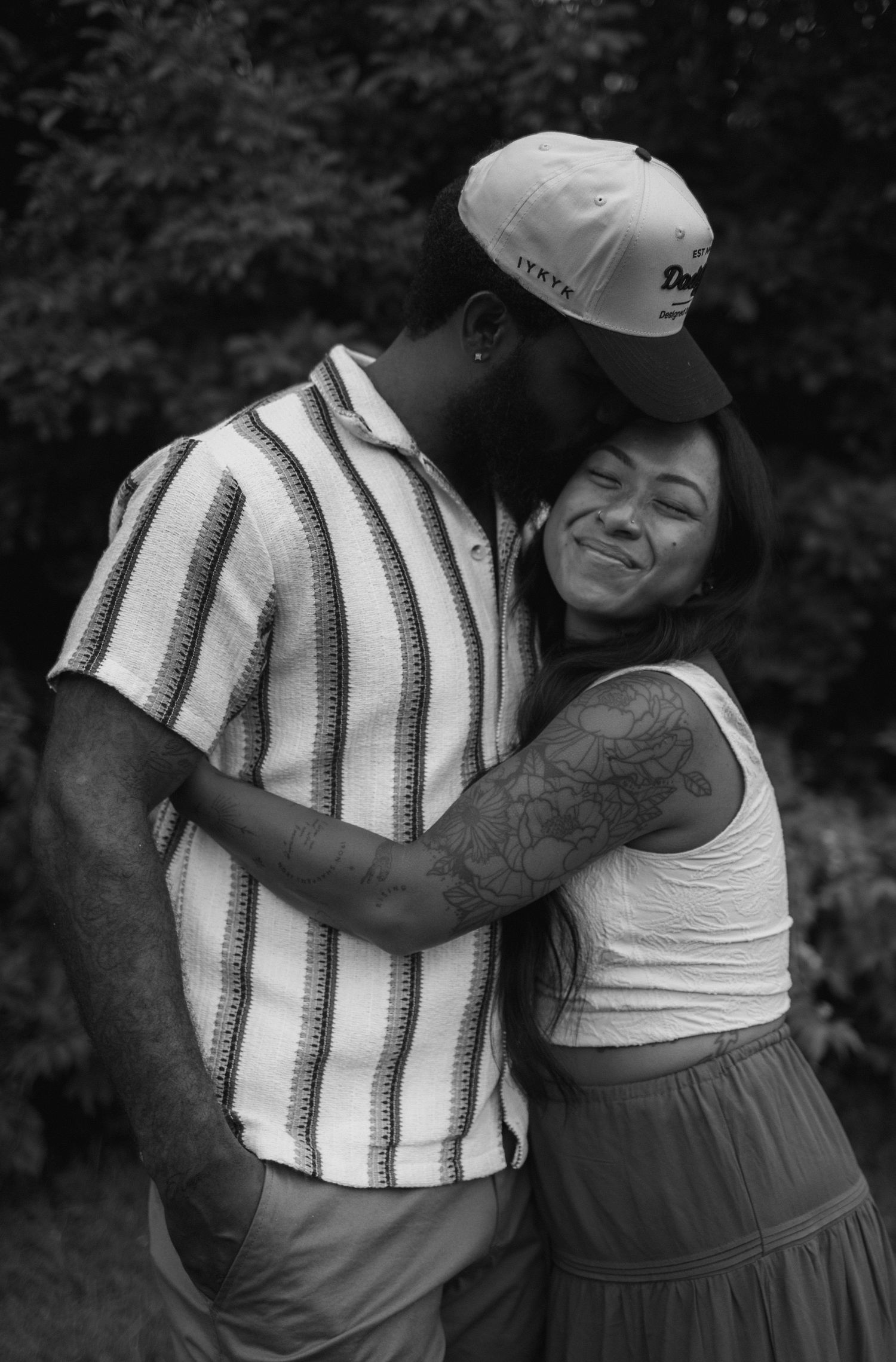 A romantic black and white photo series of a couple embracing outdoors, shown in multiple candid moments.