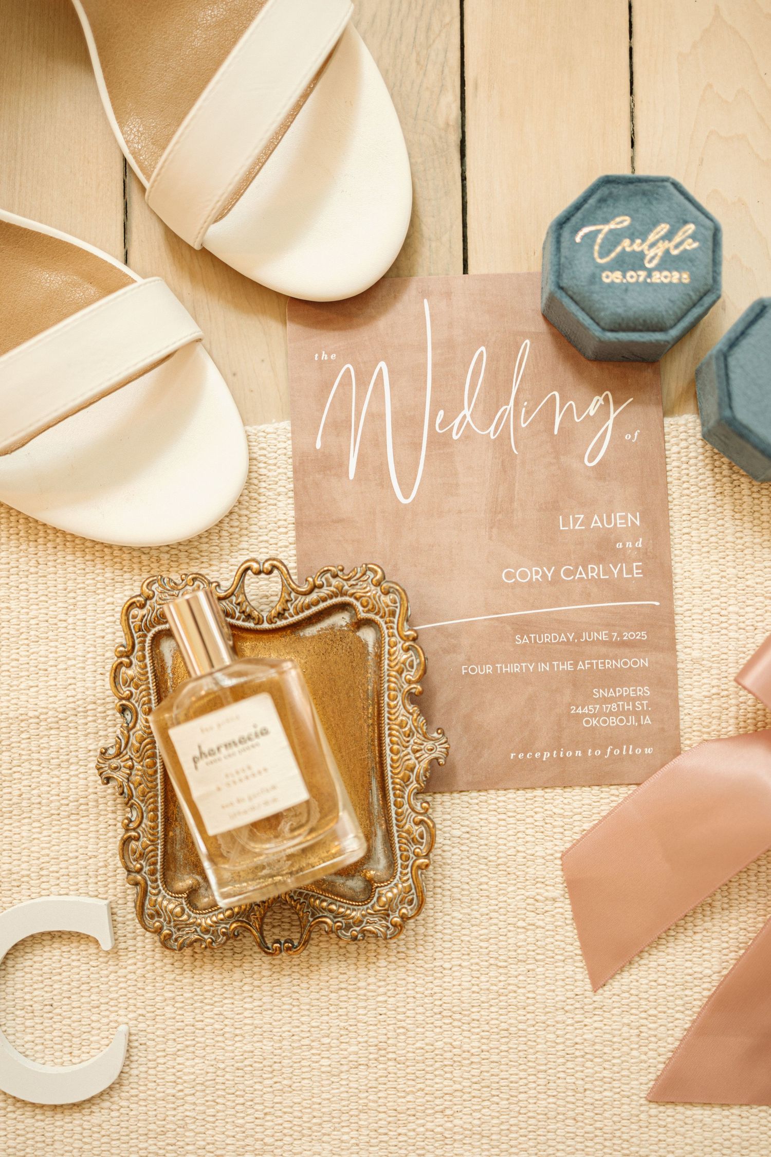 Elegant wedding details including cream ballet flats, acrylic invitation, perfume bottle in ornate frame, and teal wax seal.