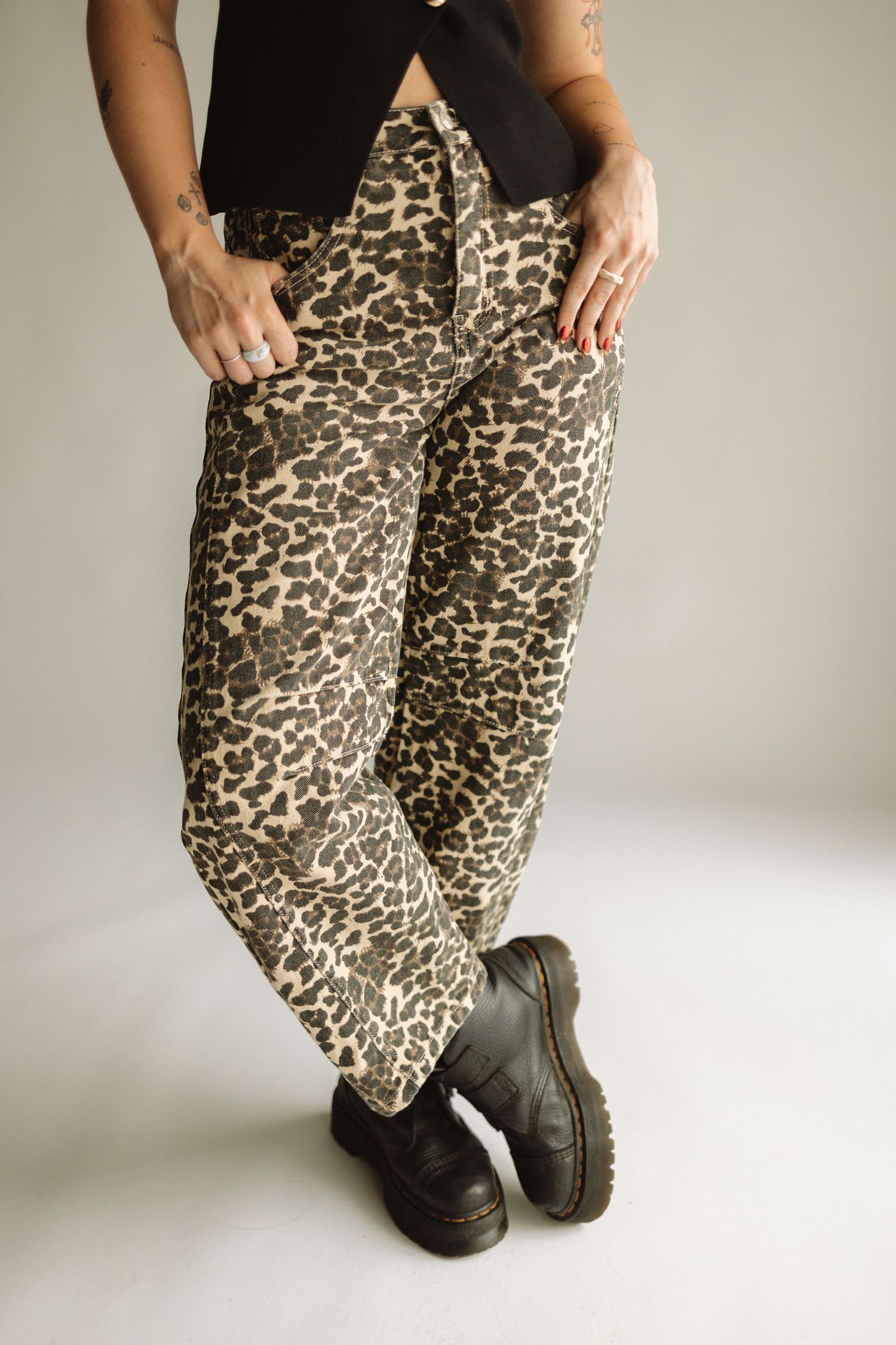 A pair of leopard print pants worn with black chunky platform shoes against a white studio background.