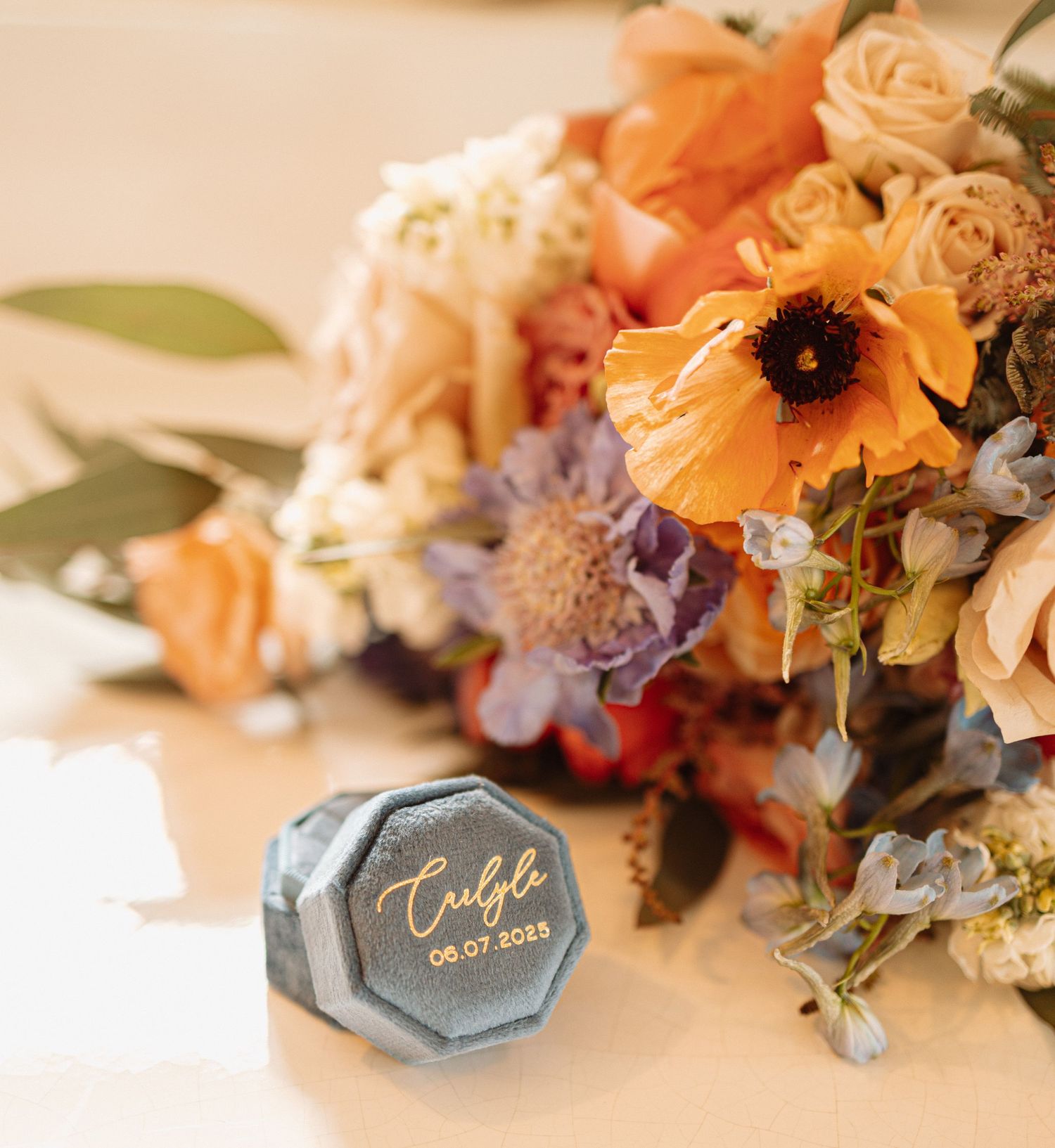 Elegant floral arrangement in peach and orange hues with sunflowers and assorted blooms next to hexagonal name cards.