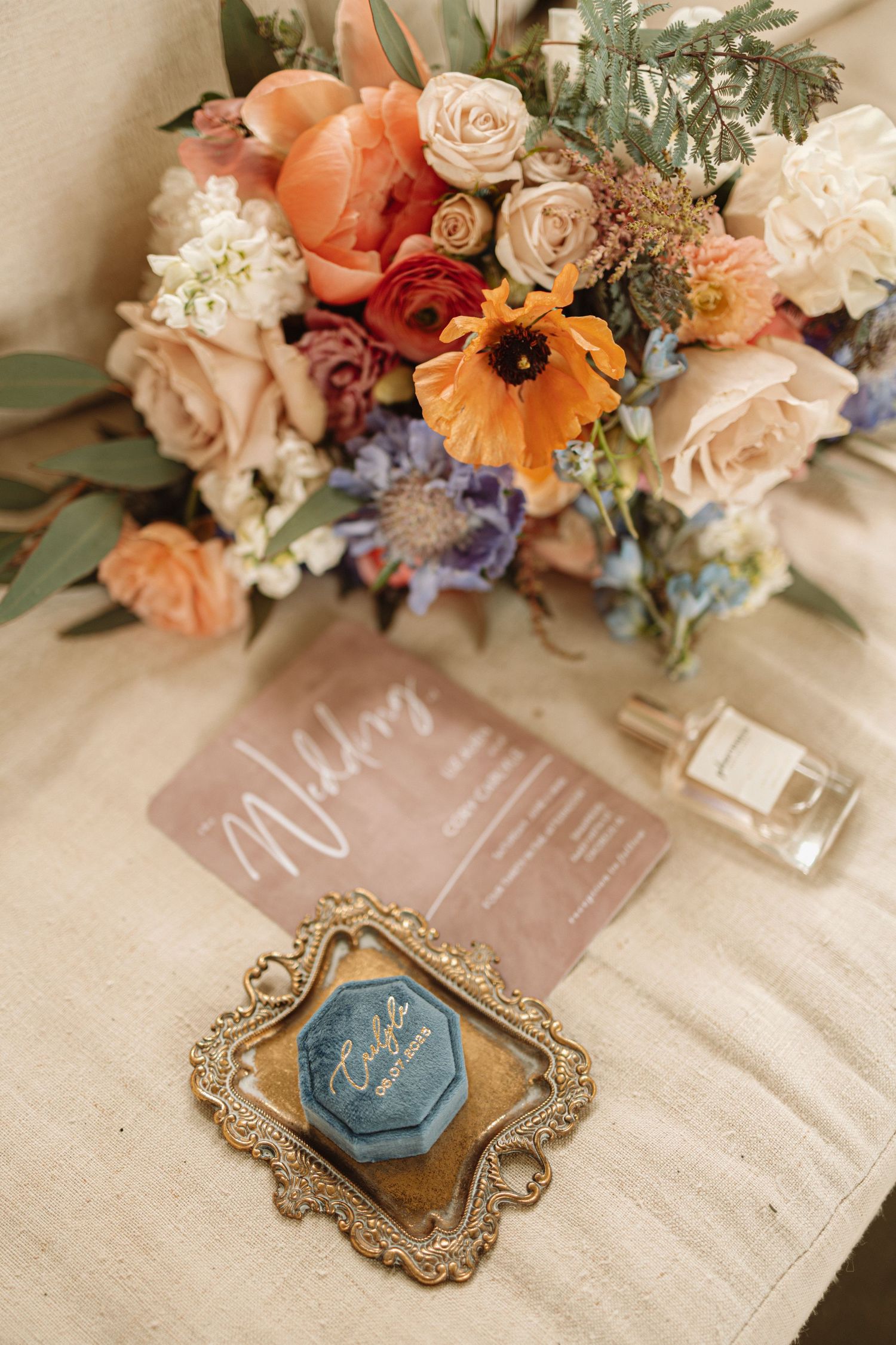 Elegant wedding place cards decorated with ornate gold frames and floral arrangements in pastel peach and blue tones.