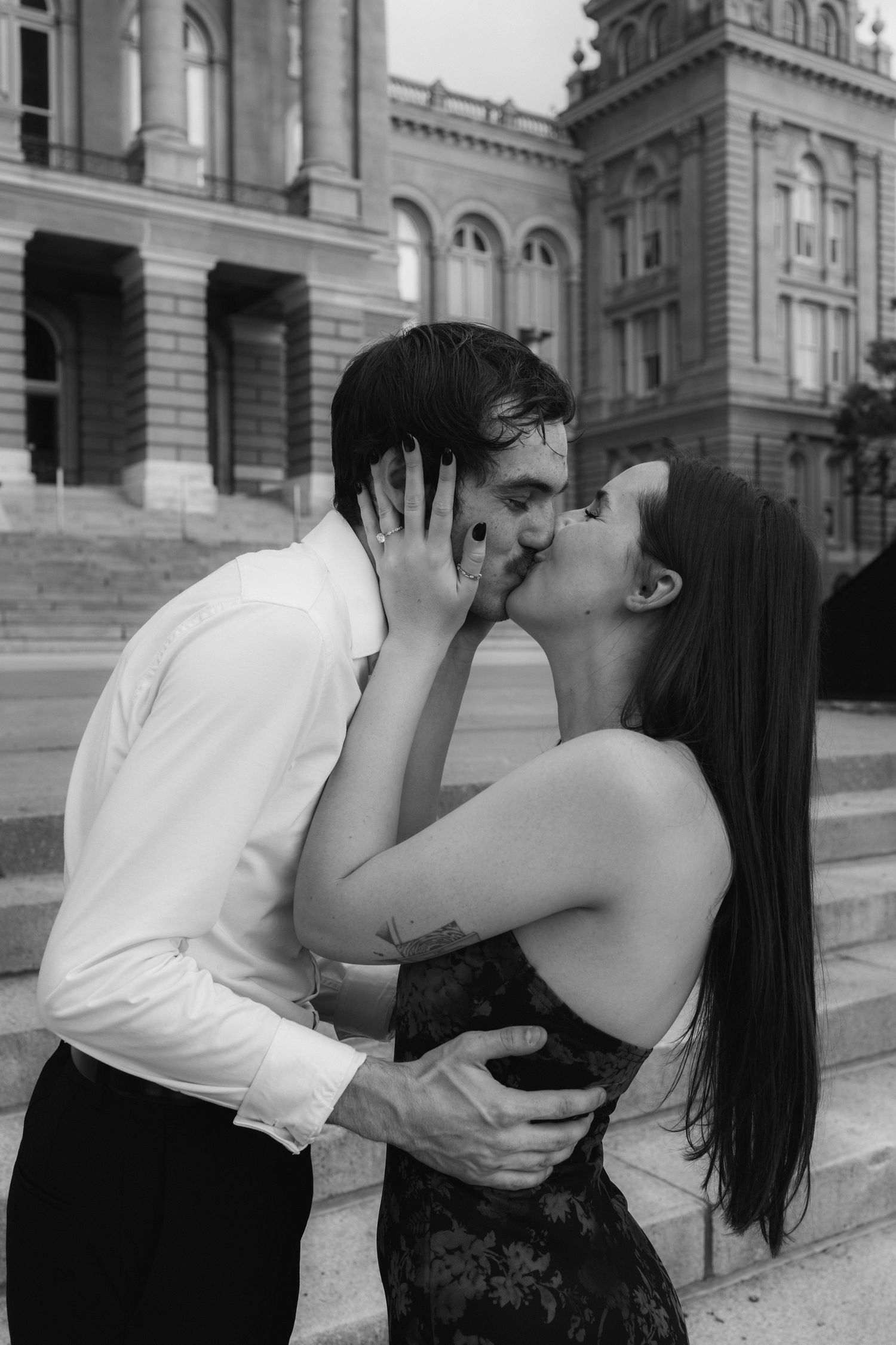 A romantic black and white photo series showing a couple kissing on stone steps of a historic building.