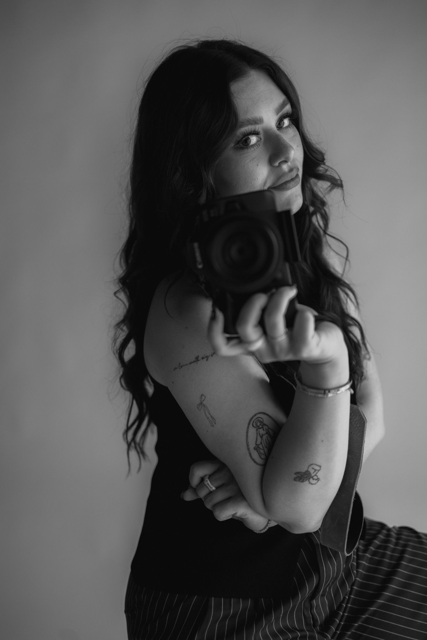 Artistic black and white portrait showing camera held against dark background.