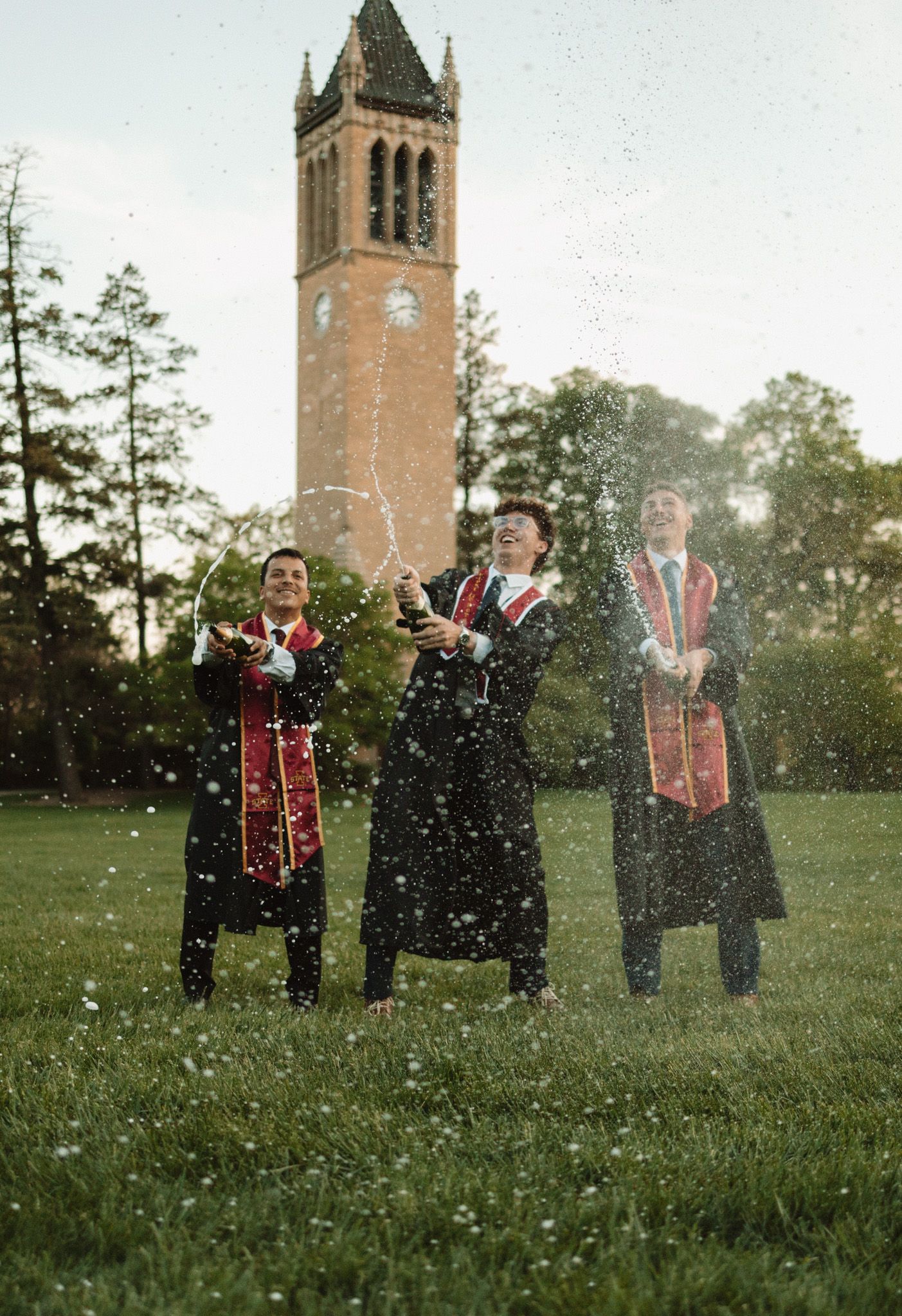 Wedding party celebrates outdoors near a historic church tower with glitter or confetti being tossed in the air.