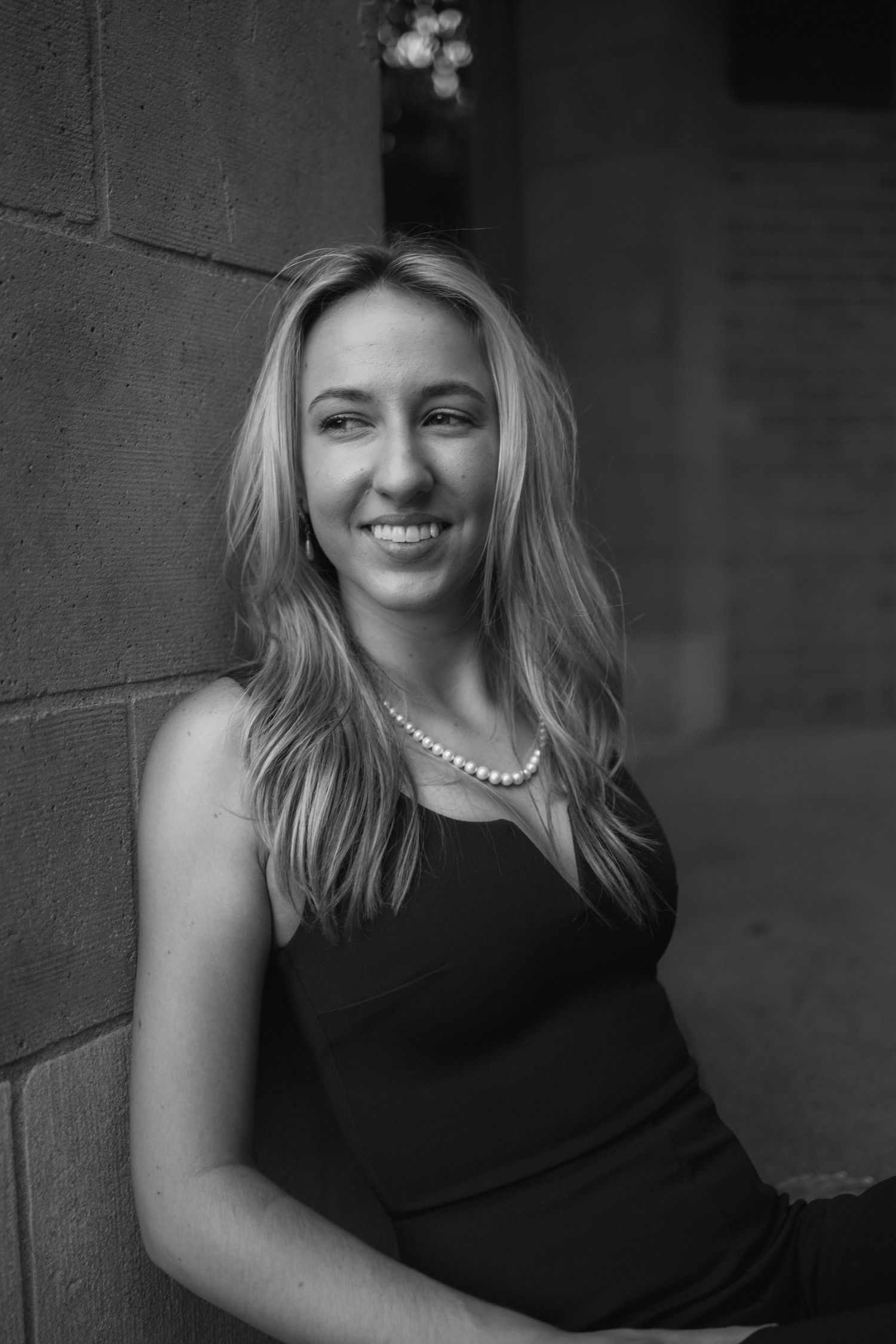 Black and white portrait series showing a woman in a sleeveless dress and pearl necklace against a dark background.