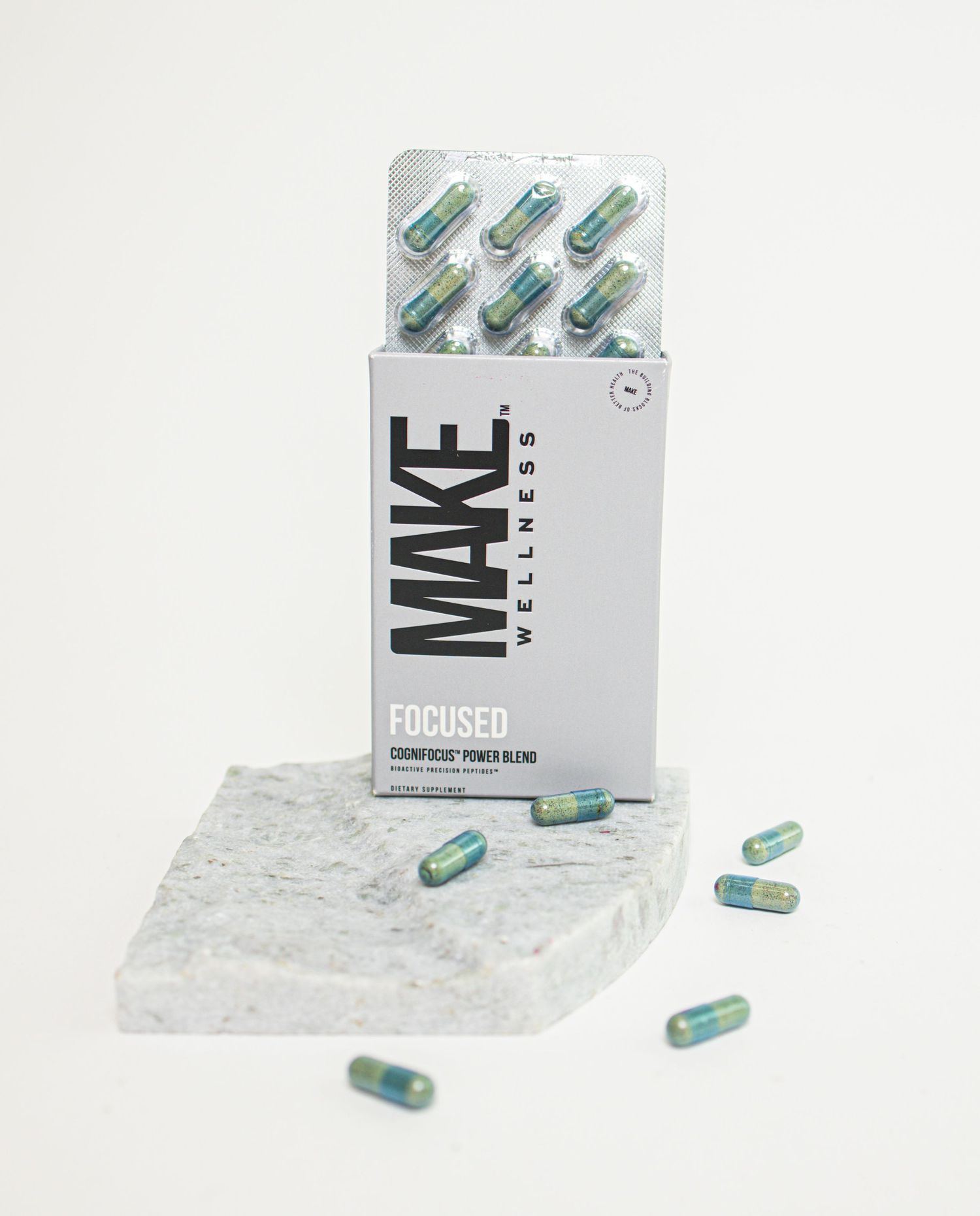 White and green pharmaceutical capsules arranged with product packaging on a white background.