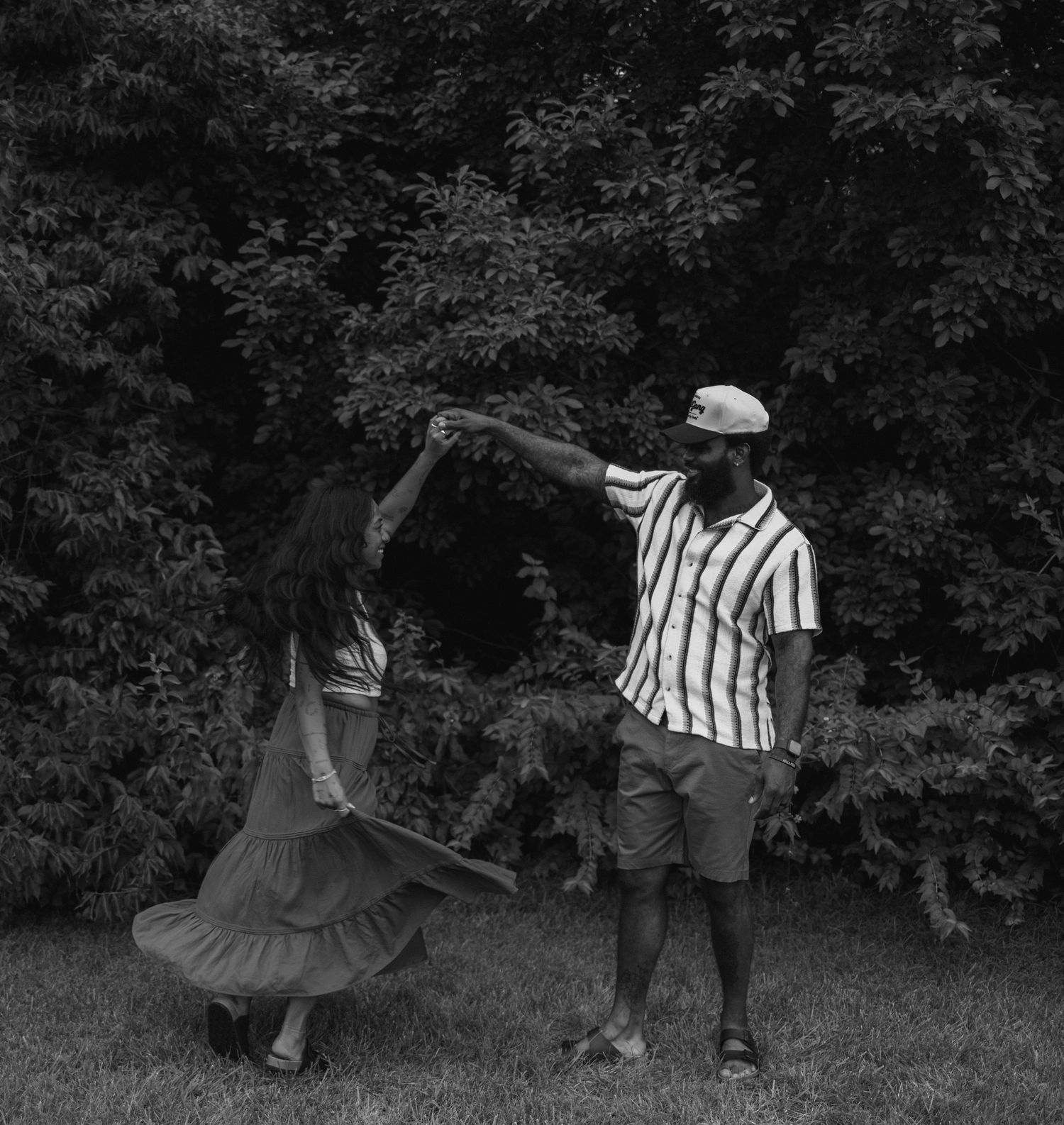 A sequence of black and white photos showing people dancing together outdoors in a natural setting.