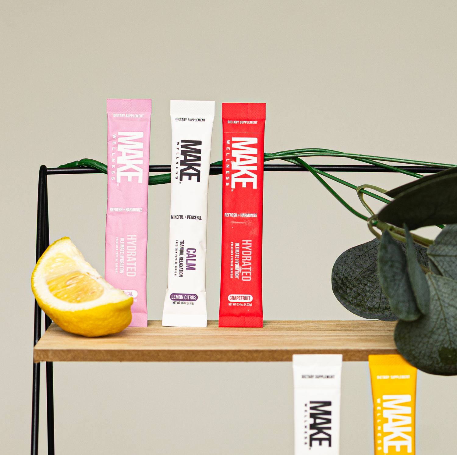 Colorful skincare product bottles arranged on wooden shelf with monstera leaf and citrus fruit decoration.