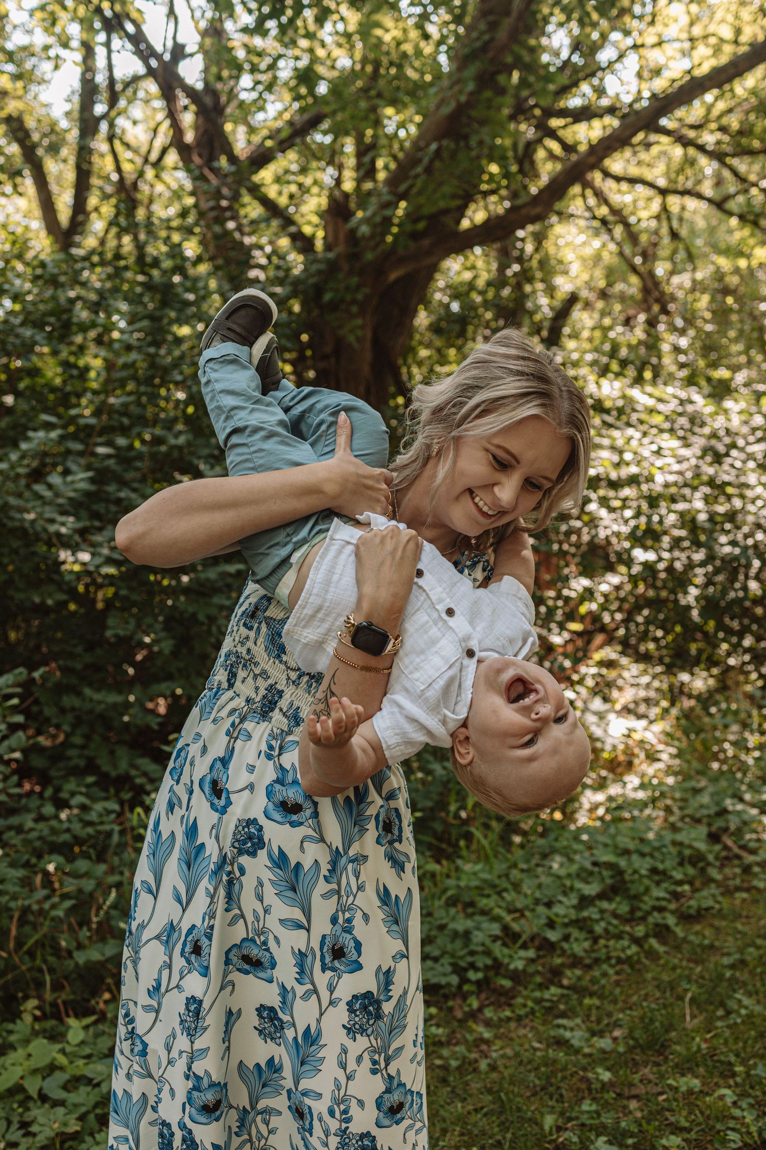 A sequence of photos showing a parent in a floral dress feeding a baby outdoors in a natural garden setting.