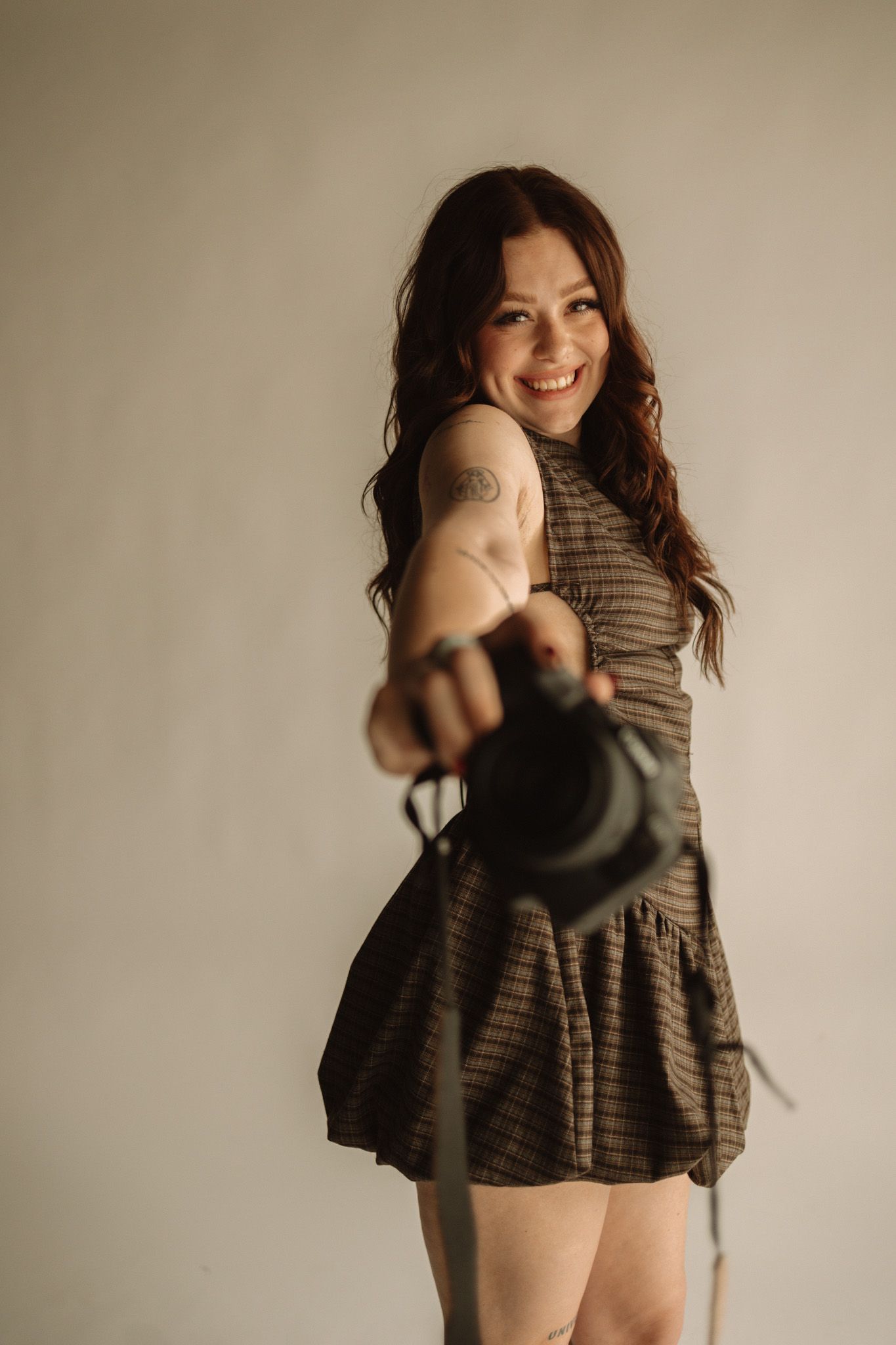 A person in a striped dress twirls playfully in front of a neutral wall background creating a series of motion shots.