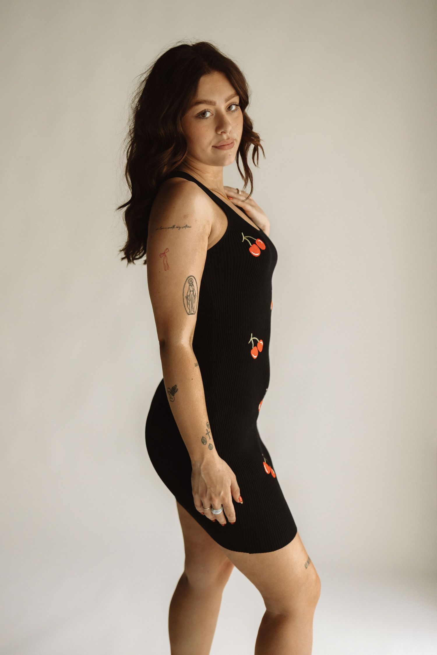 A figure in a black swimsuit with floral details poses in different positions against a white backdrop for a fashion photo series.
