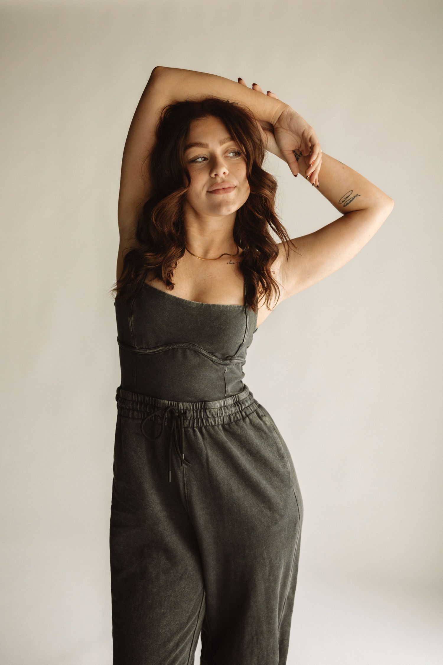 Fashion photoshoot featuring a modern minimalist romper outfit in olive green against a light neutral background.
