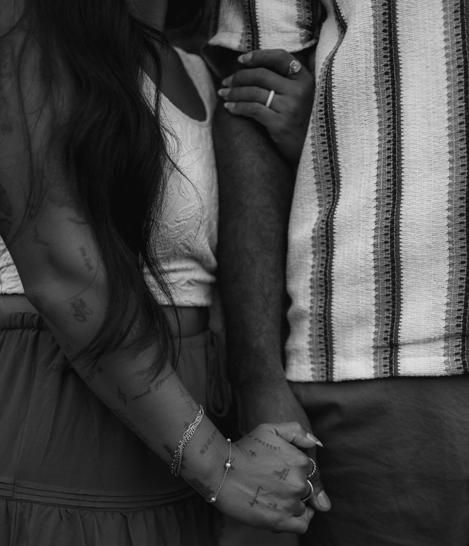 Black and white artistic portrait showing hands together against a striped background in dim lighting.