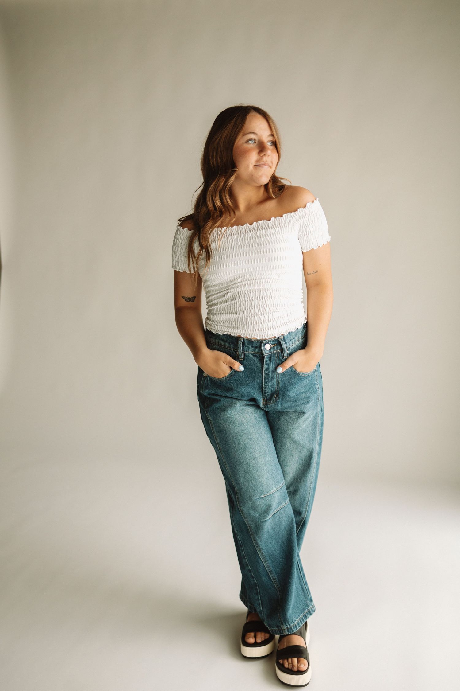 Casual outfit featuring white smocked top and wide-leg denim jeans paired with sandals.