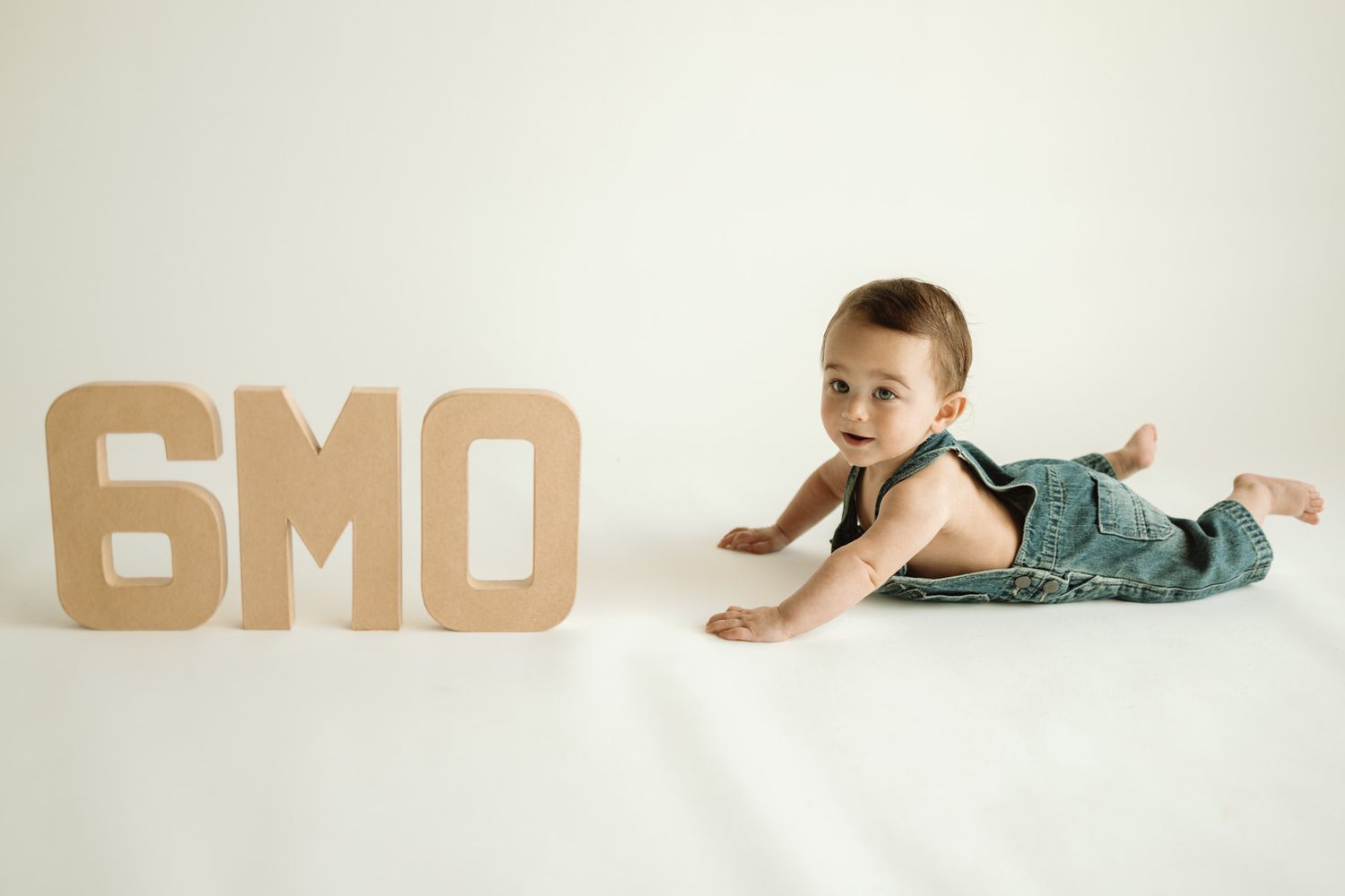 A series of cropped letter blocks spelling GMO in metallic sandy tones shows a progressive perspective view.