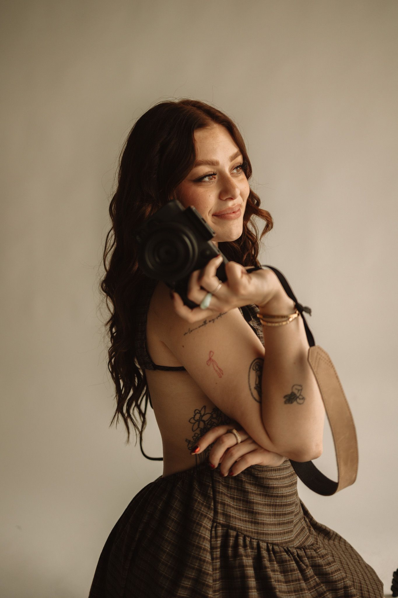 Woman in dark brown dress poses against neutral wall in artistic lifestyle photoshoot sequence.