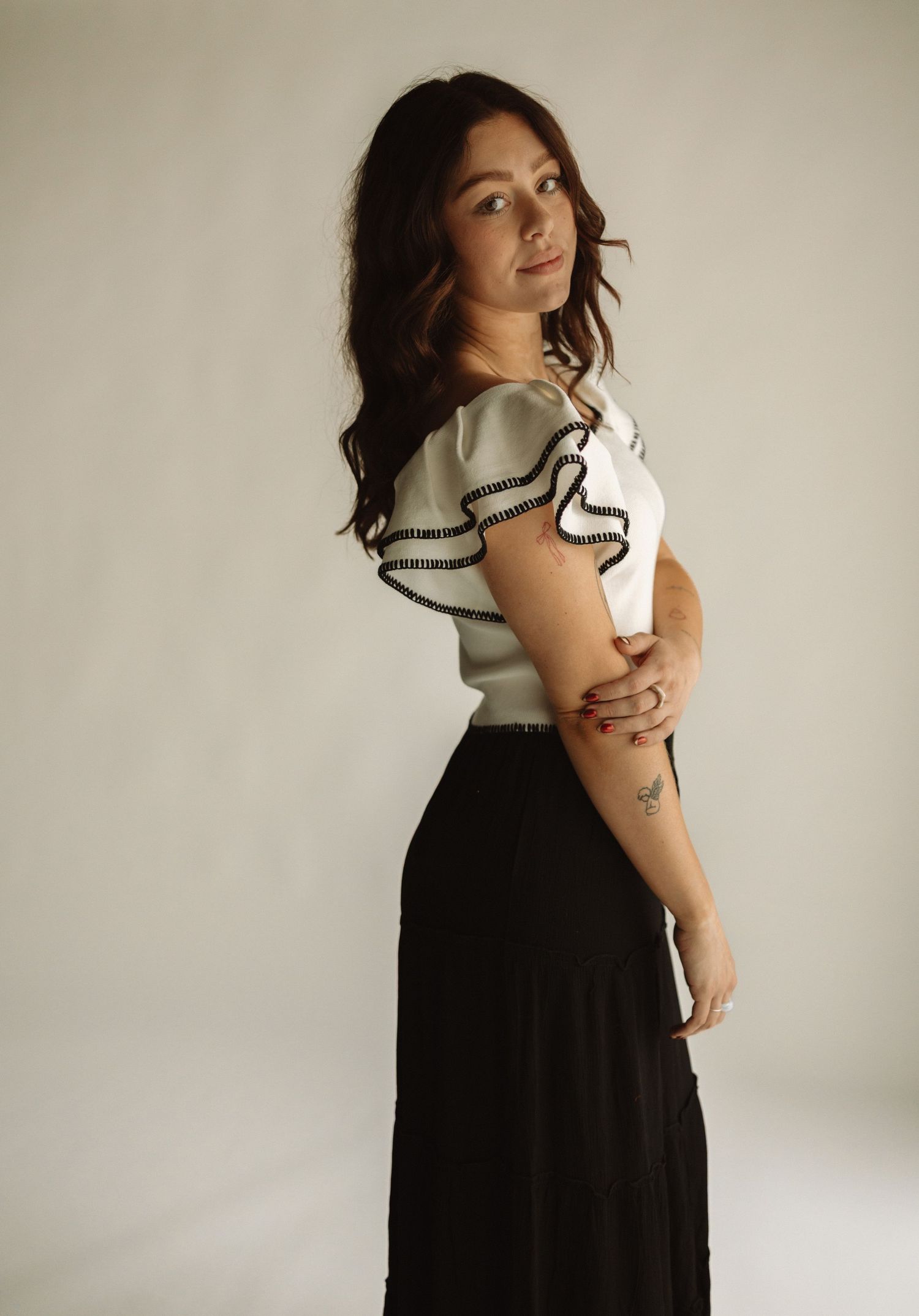 A series of artistic portrait photographs showing someone in a black dress and white turtleneck posing against a light background.
