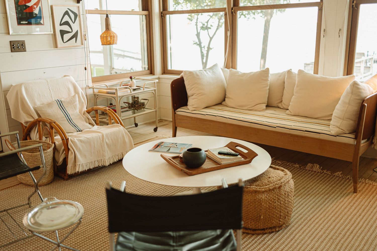 A bright modern living room features five white armchairs and sofas with beige accents and woven decor elements.