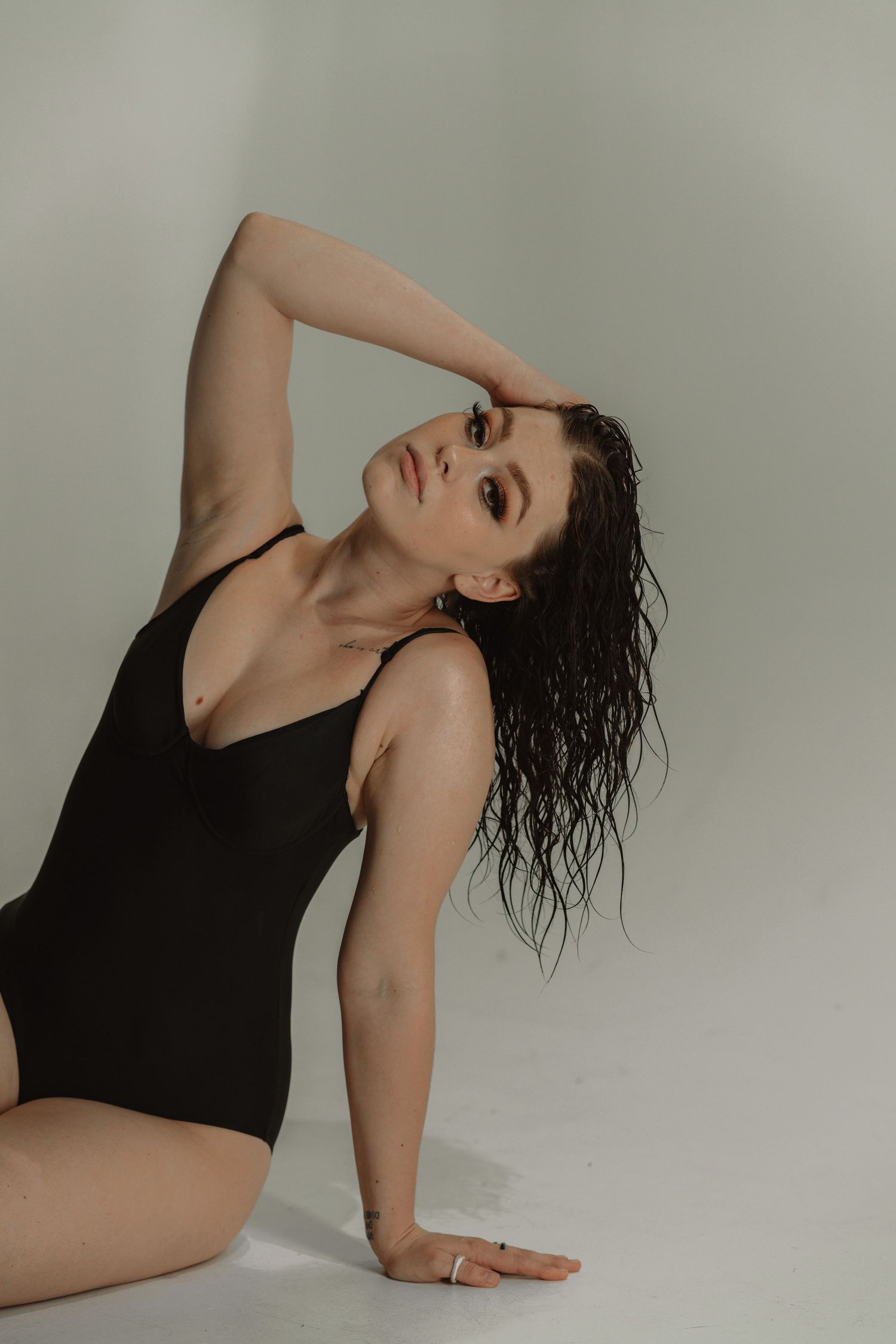 Artistic portrait series showing a figure in black against neutral background posing with wet hair in dramatic positions.