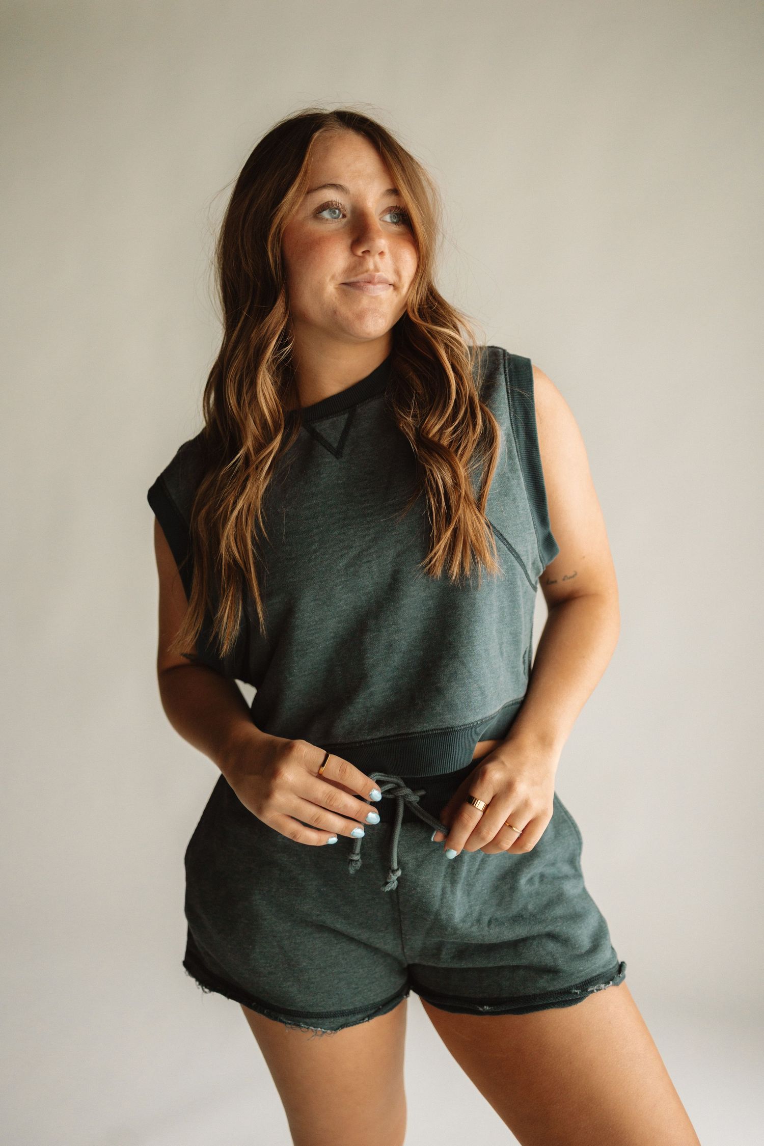 Woman in dark sleeveless top and shorts poses casually while showing the comfort and fit from multiple angles.