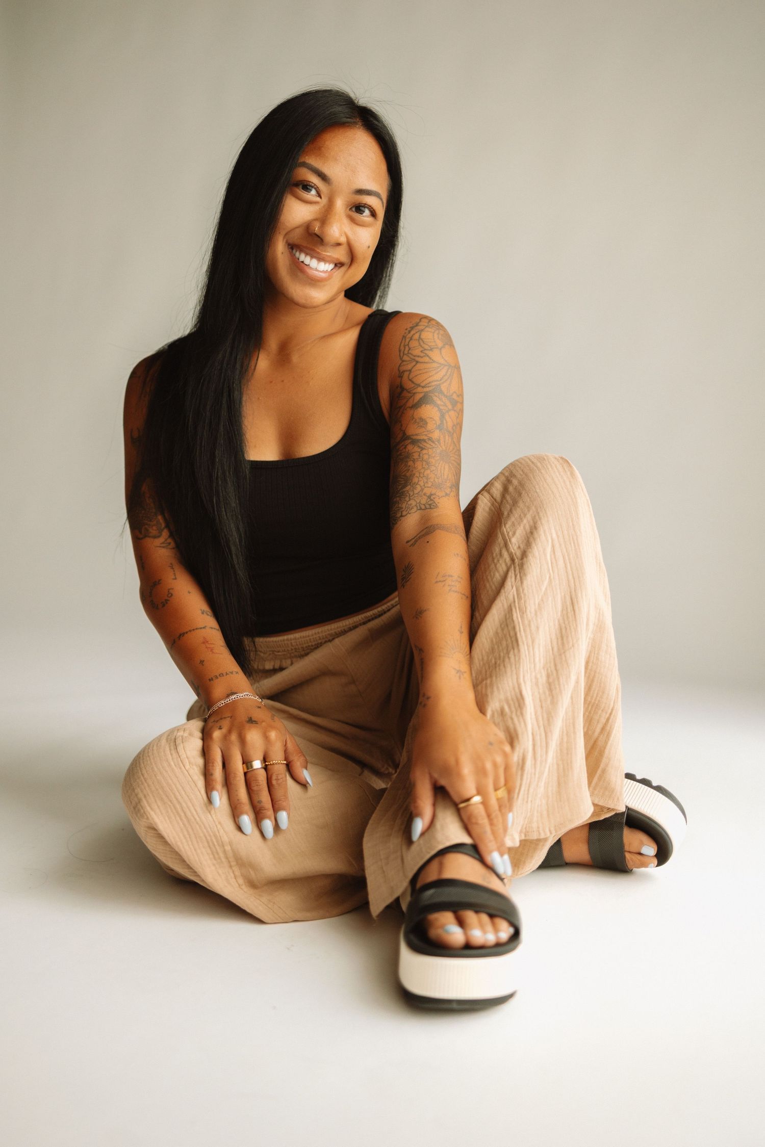 Portrait session showing casual poses against white background wearing black top and beige pants.
